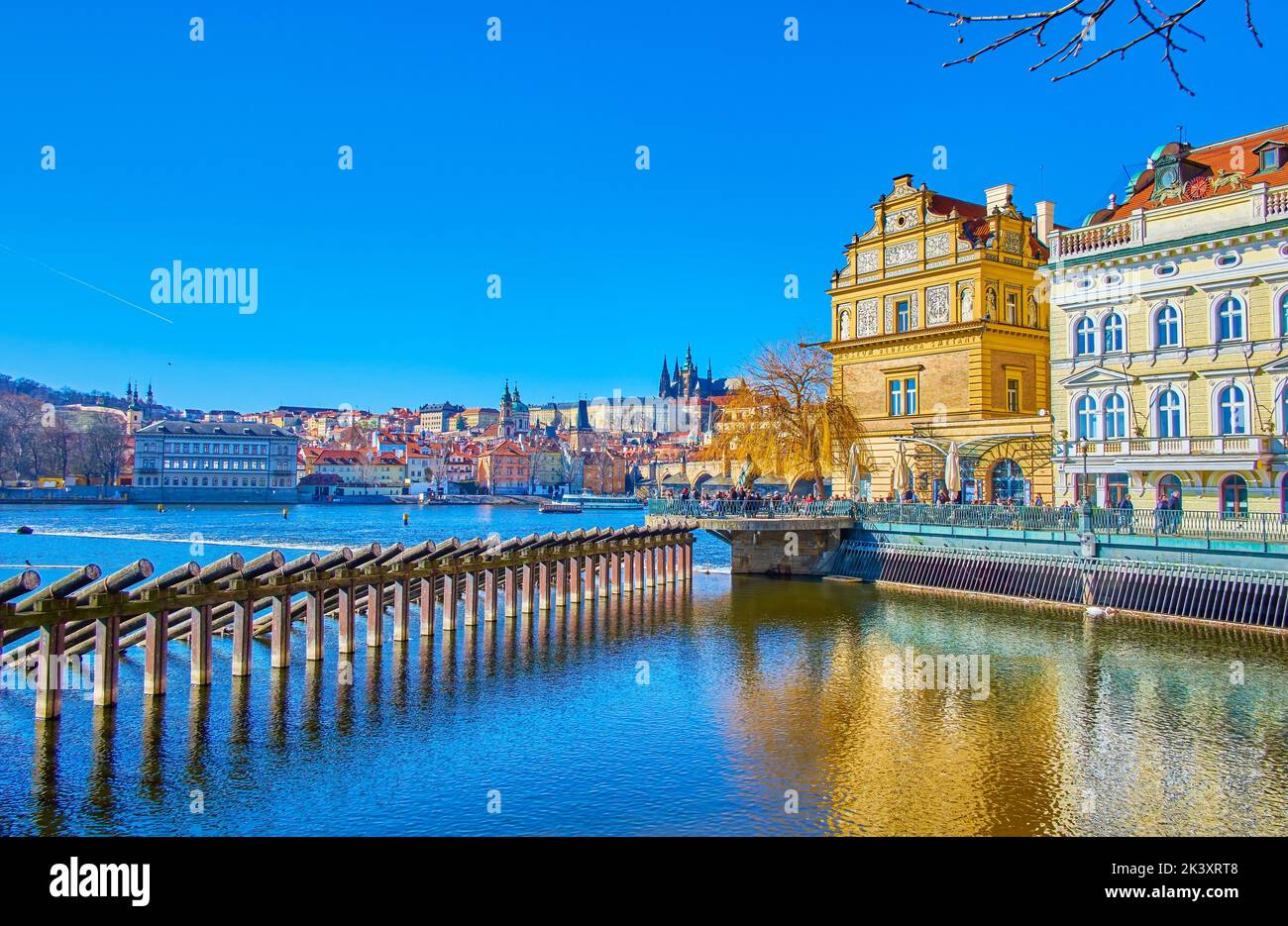 Outdoor restaurants on Smetana Embankment and wooden icebreakers of Vltava river in Prague, Czech Republic Stock Photo