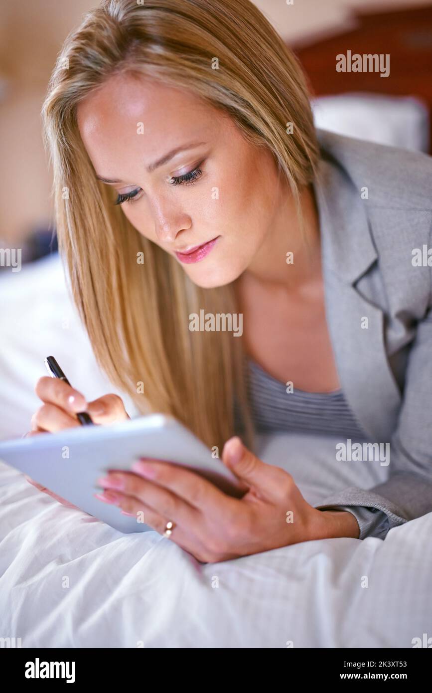 The features on this tablet cater to my every need. A young businesswoman using a digital tablet in a bedroom. Stock Photo