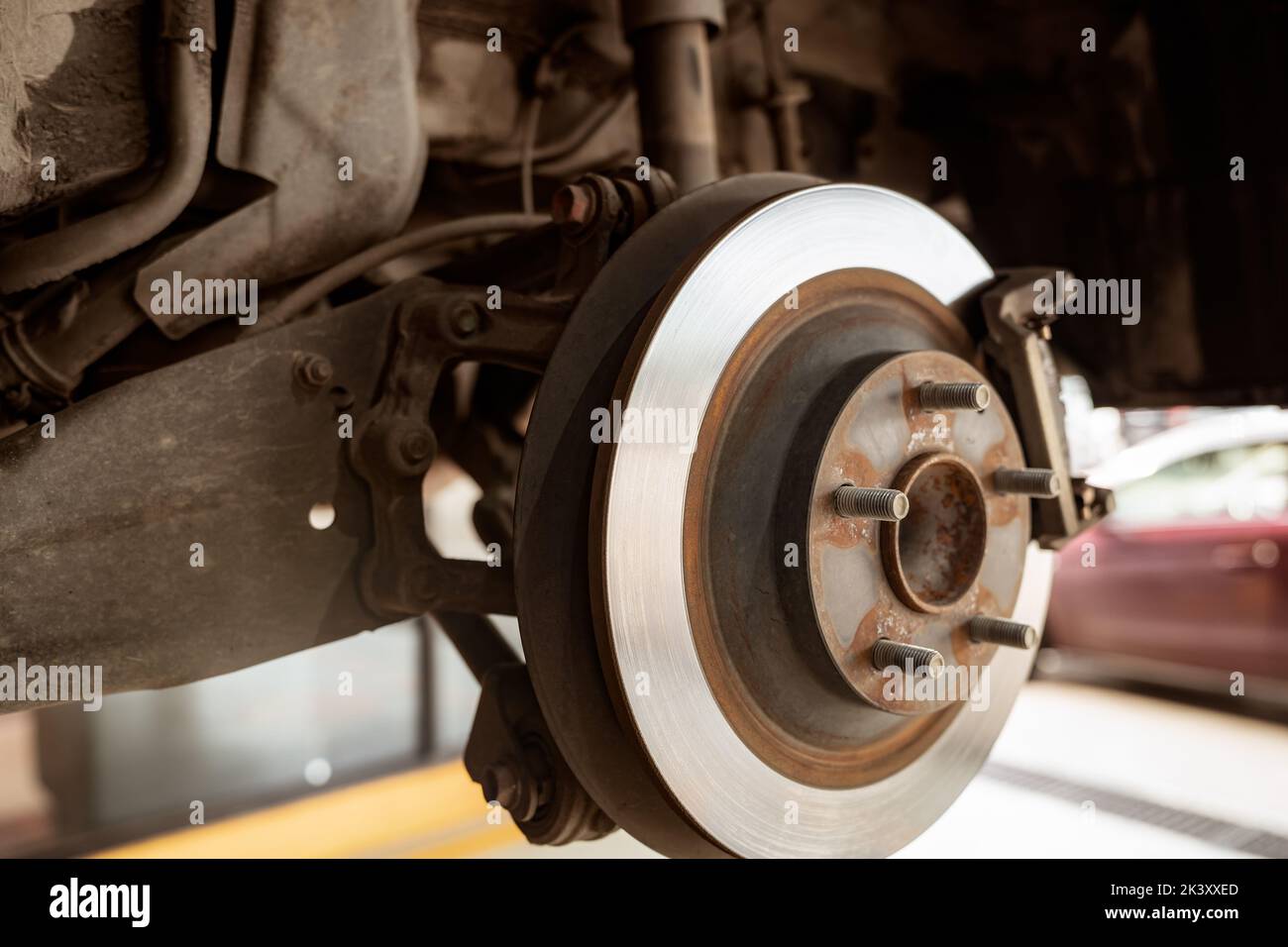 Car disc brake system. Car suspension in process of new tire replacement at garage workshop. Car disc brake mechanic check and repair. Disk break roto Stock Photo