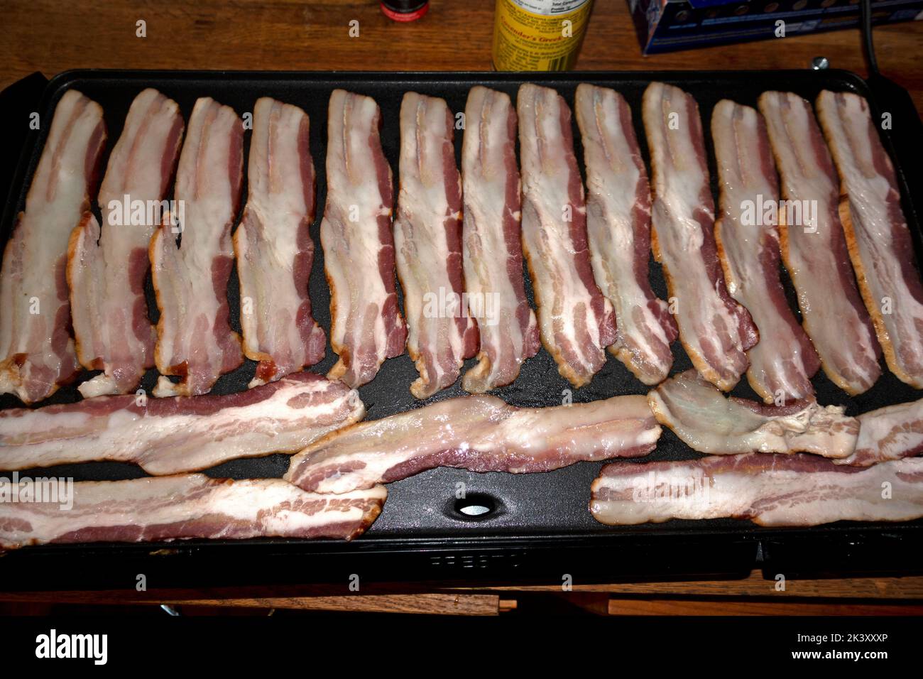 Artistically arranged bacon frying on a portable electric grill at home. Clitherall Minnesota MN USA Stock Photo