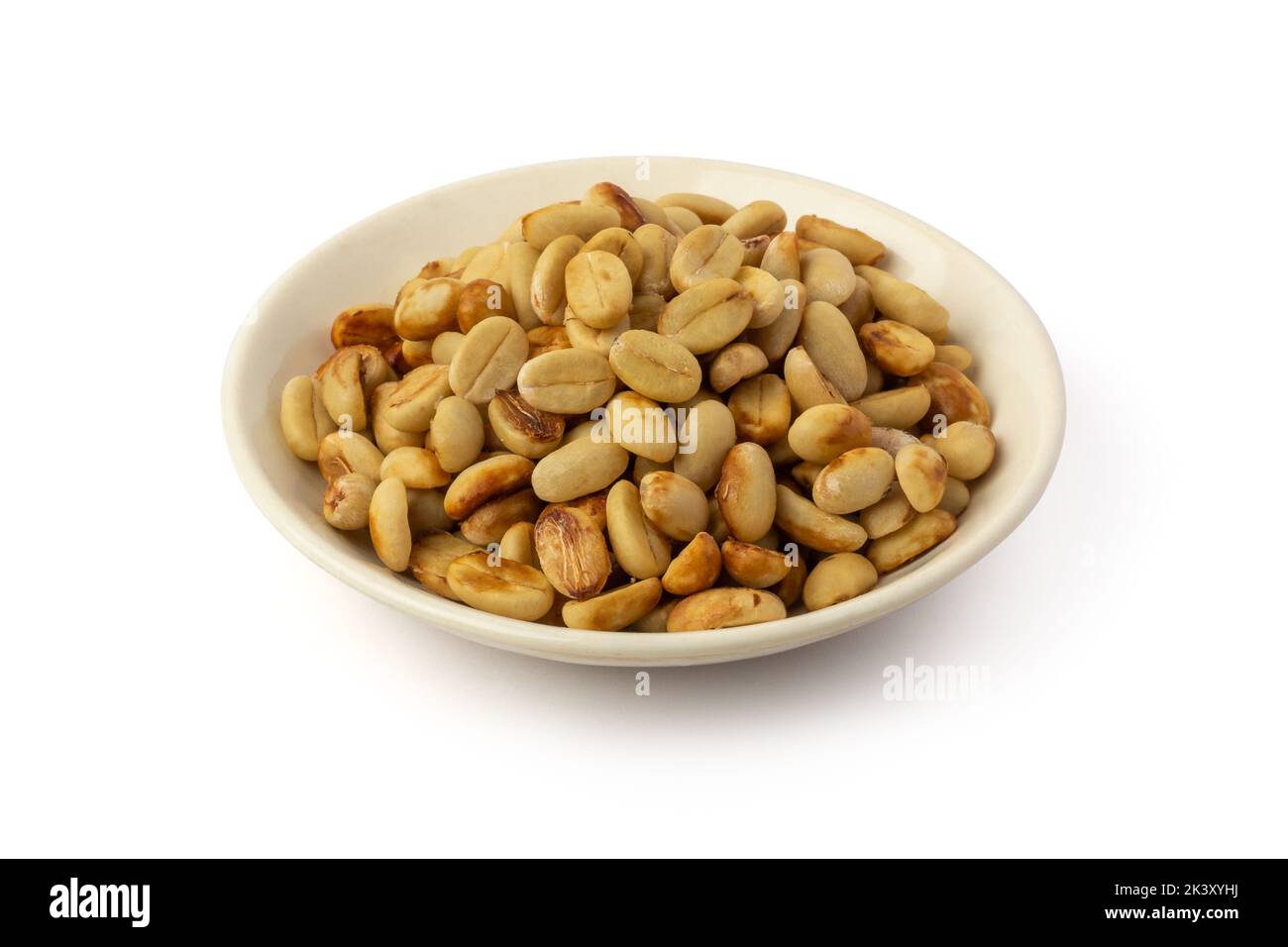 dried coffee beans with hull or parchment skin on white plate, coffea arabica, pulp and skin or flesh of the coffee cherry is removed from the beans Stock Photo