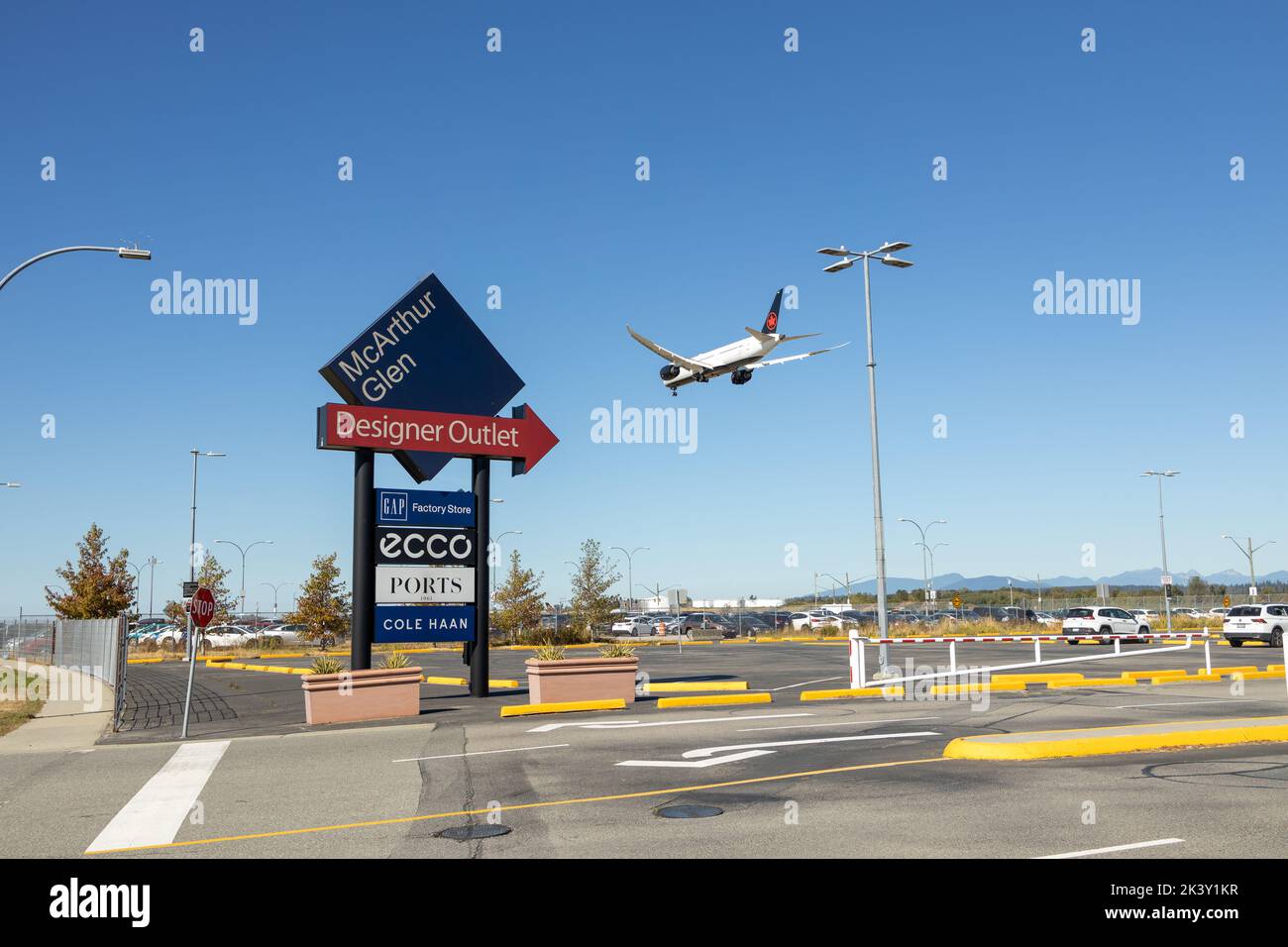 Vancouver, Canada - September 25, 2022: View of sign McArthur Glen Designer Outlet with landing plane in the background Stock Photo