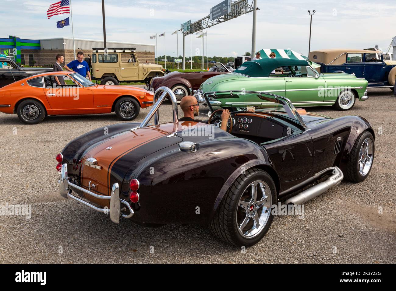 A man drives a brown Shelby AC 427 Cobra replica sports car into line prior to Worldwide Auctioneers 2022 Auburn Auction in Auburn, Indiana, USA. Stock Photo