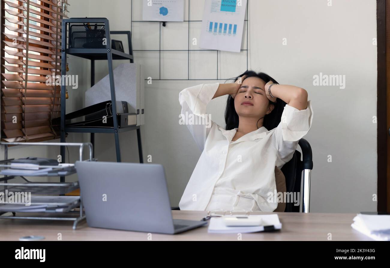 Tired business accountant woman feel headache. stressed working woman at business desk in a business office Stock Photo