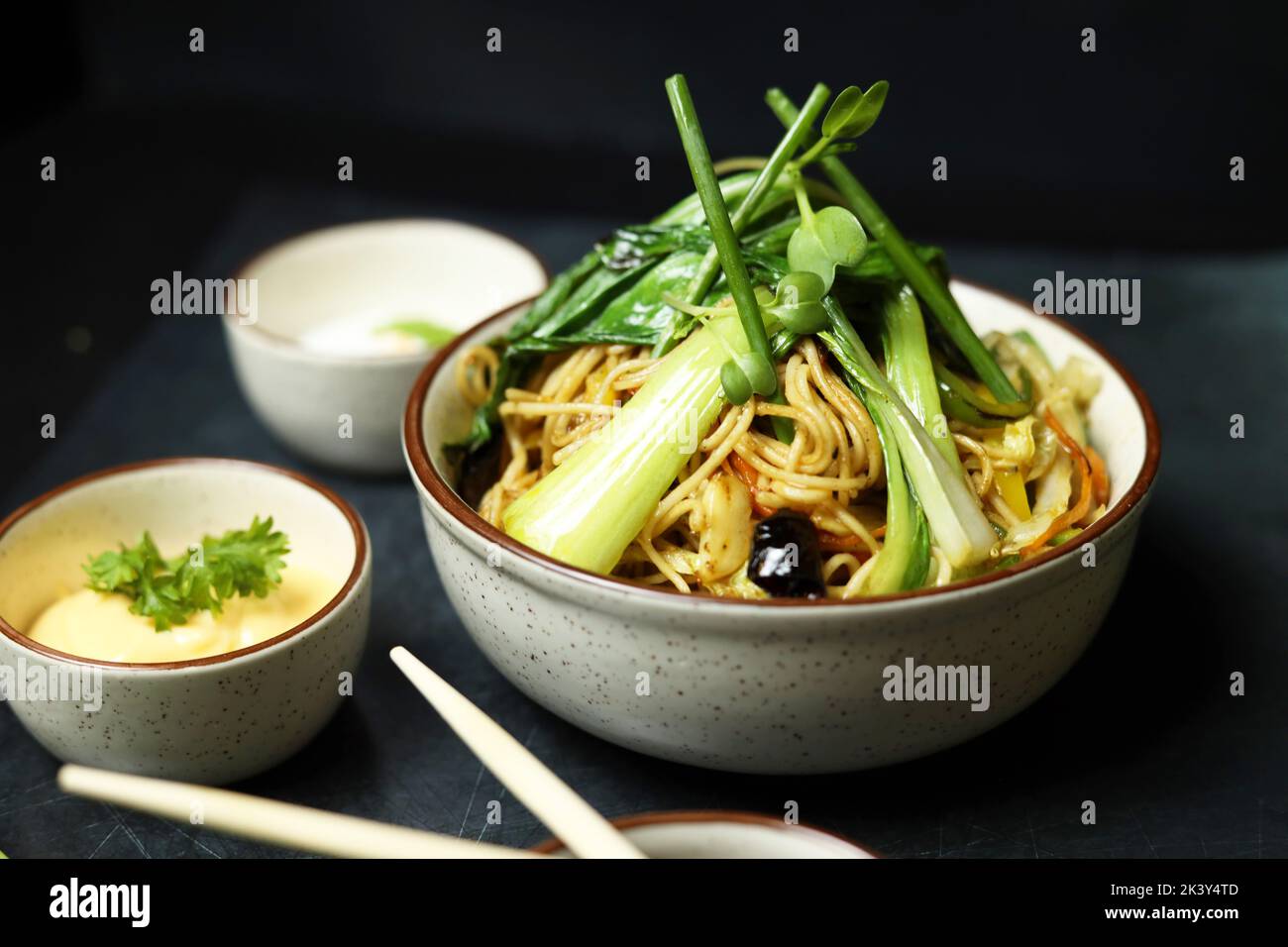 Noodles in bowl with chopsticks soya sauce and spring onions Stock Photo