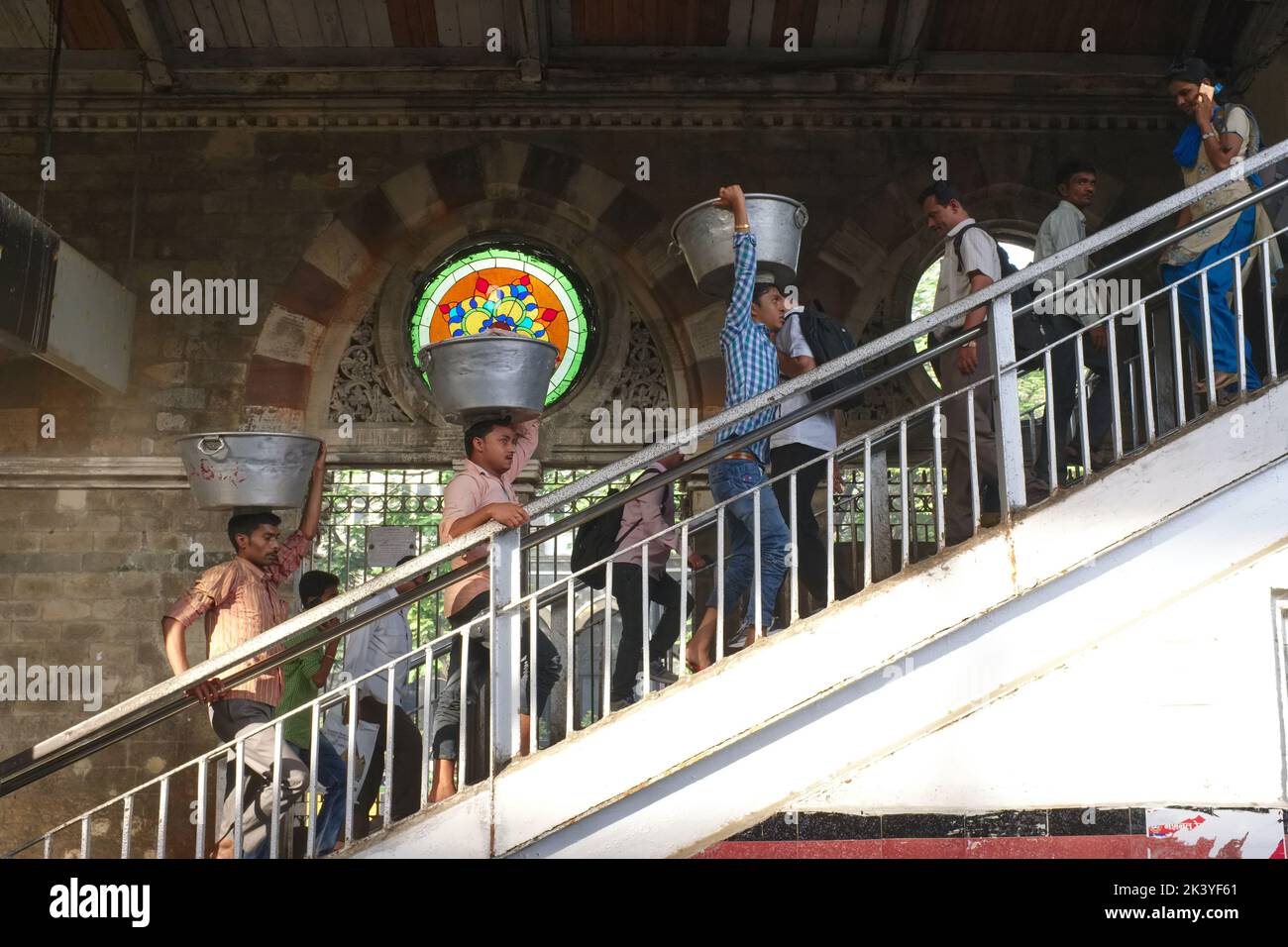 Indian men carrying goods on their heads, ascending a staircase at Chhatrapati Shivaji Maharaj Terminus in Mumbai, India Stock Photo
