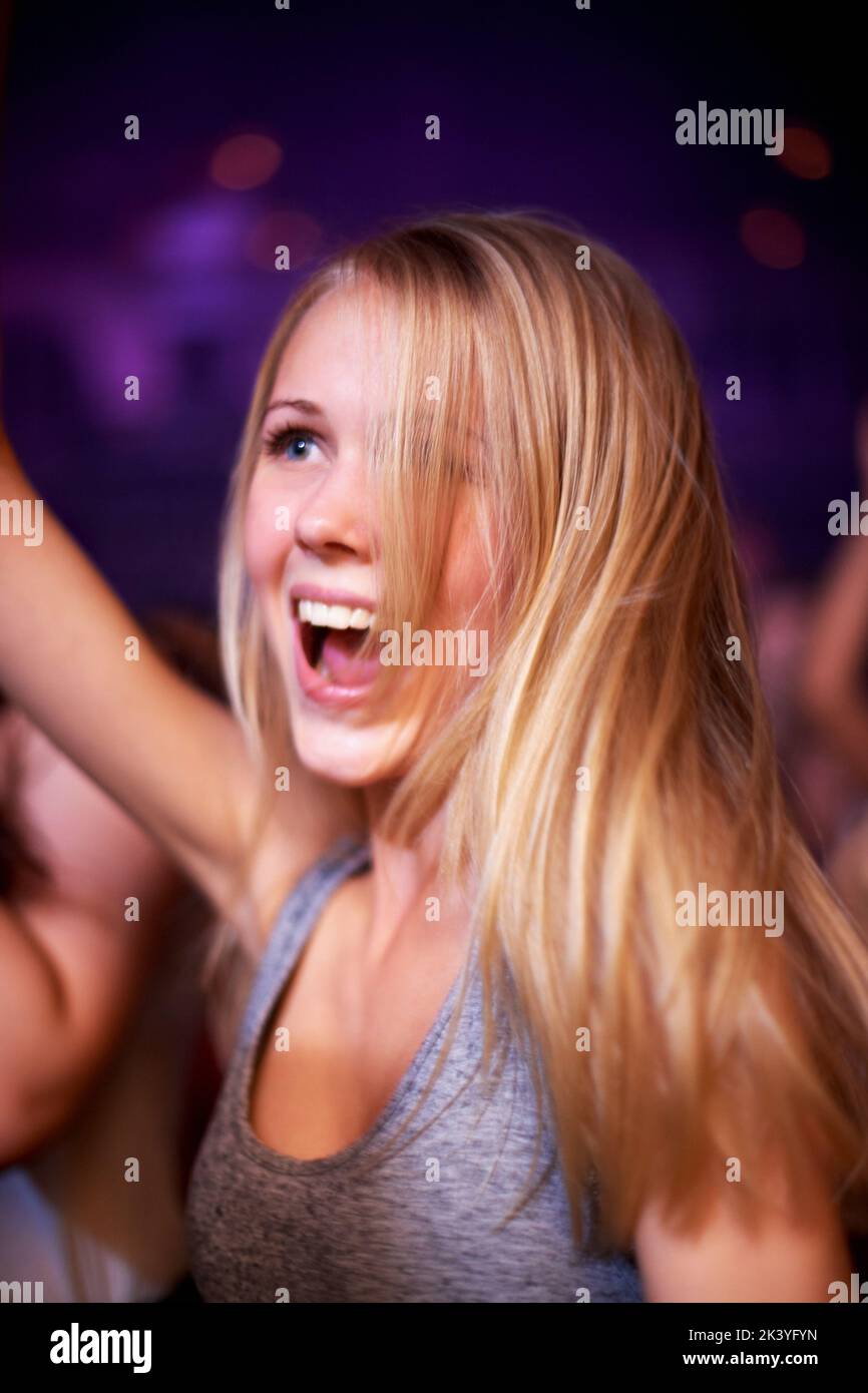 This is my favourite band. A young woman dancing in a crowd at a concert. Stock Photo