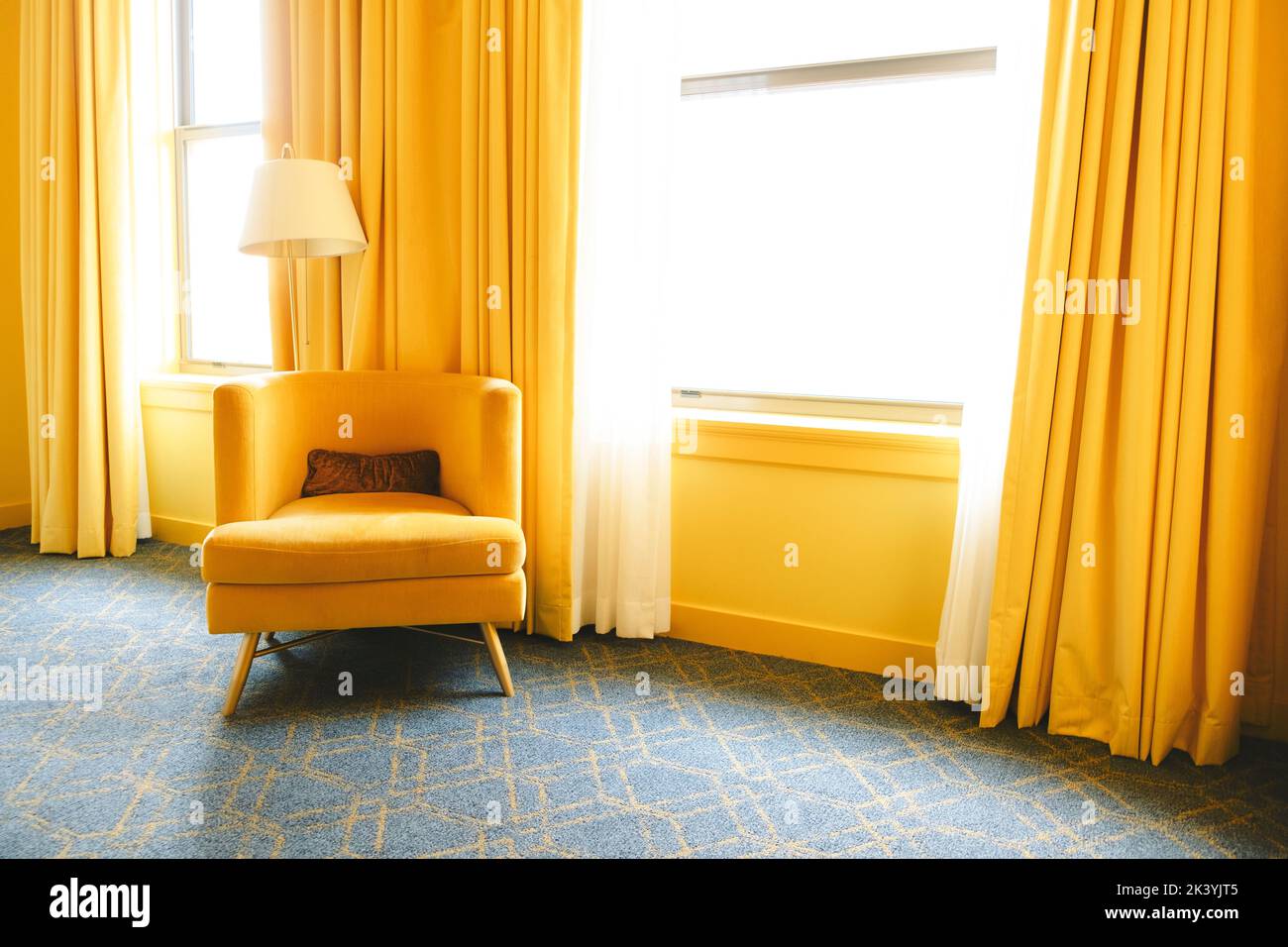 An interior of a bright room with yellow curtains and a yellow reading