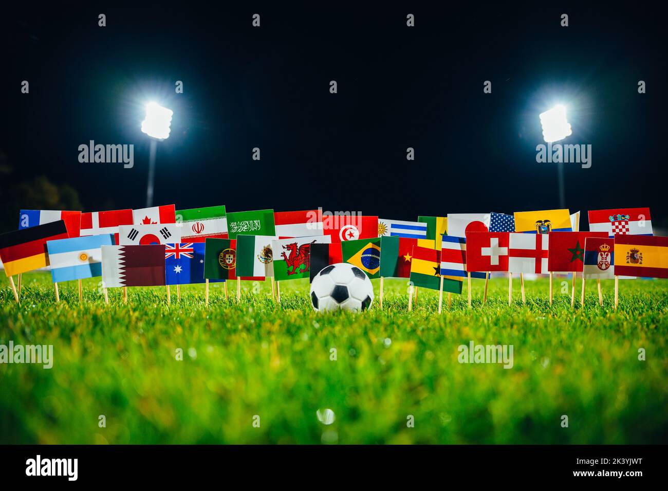 Football ball and 32 national flags on green grass Stock Photo