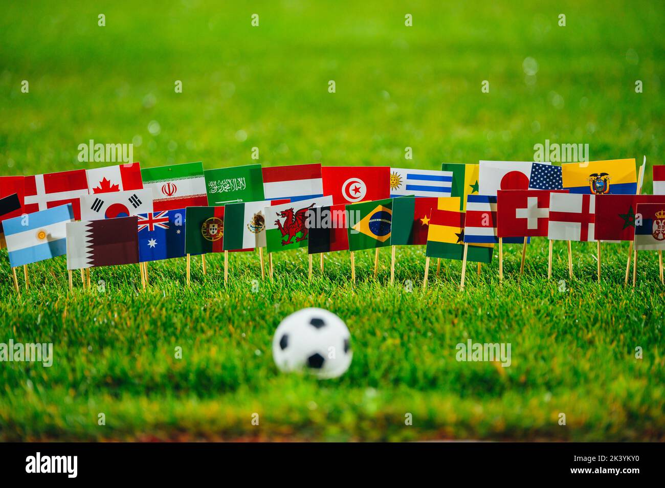 Football ball on green grass and all 32 national flags. Wallpaper for football Tournament Stock Photo