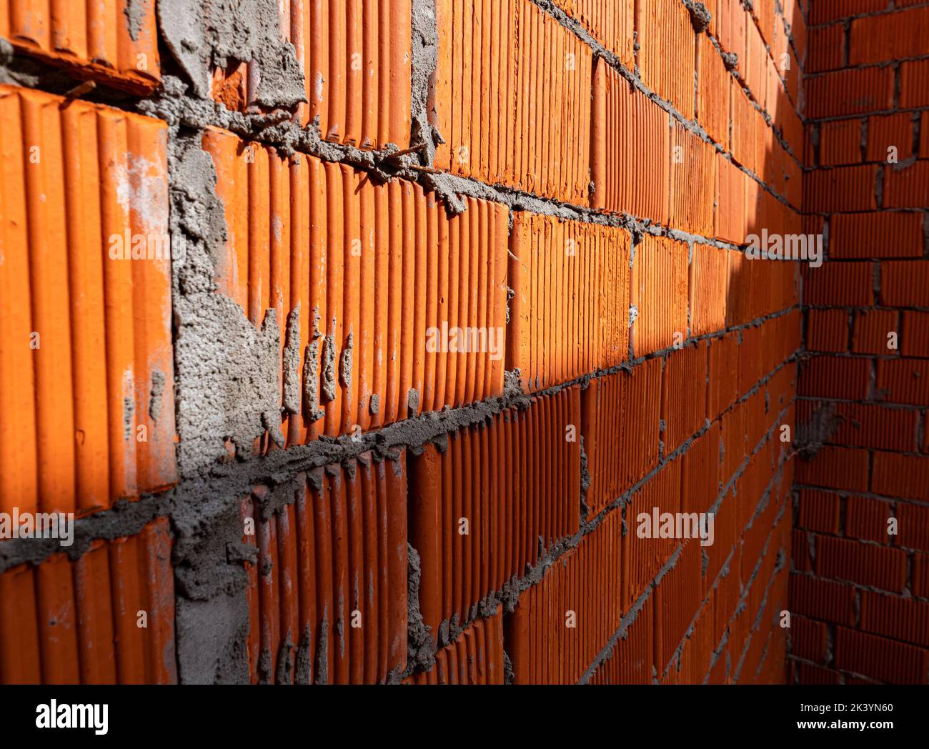 Brick wall of rough masonry. Large bricks in close-up. Walls in roughing. Brick wall texture. A spot of light on a brick wall Stock Photo