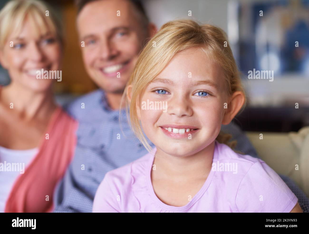 Shes so precious to her parents. A cute young girl smiling as her parents sit proudly in the