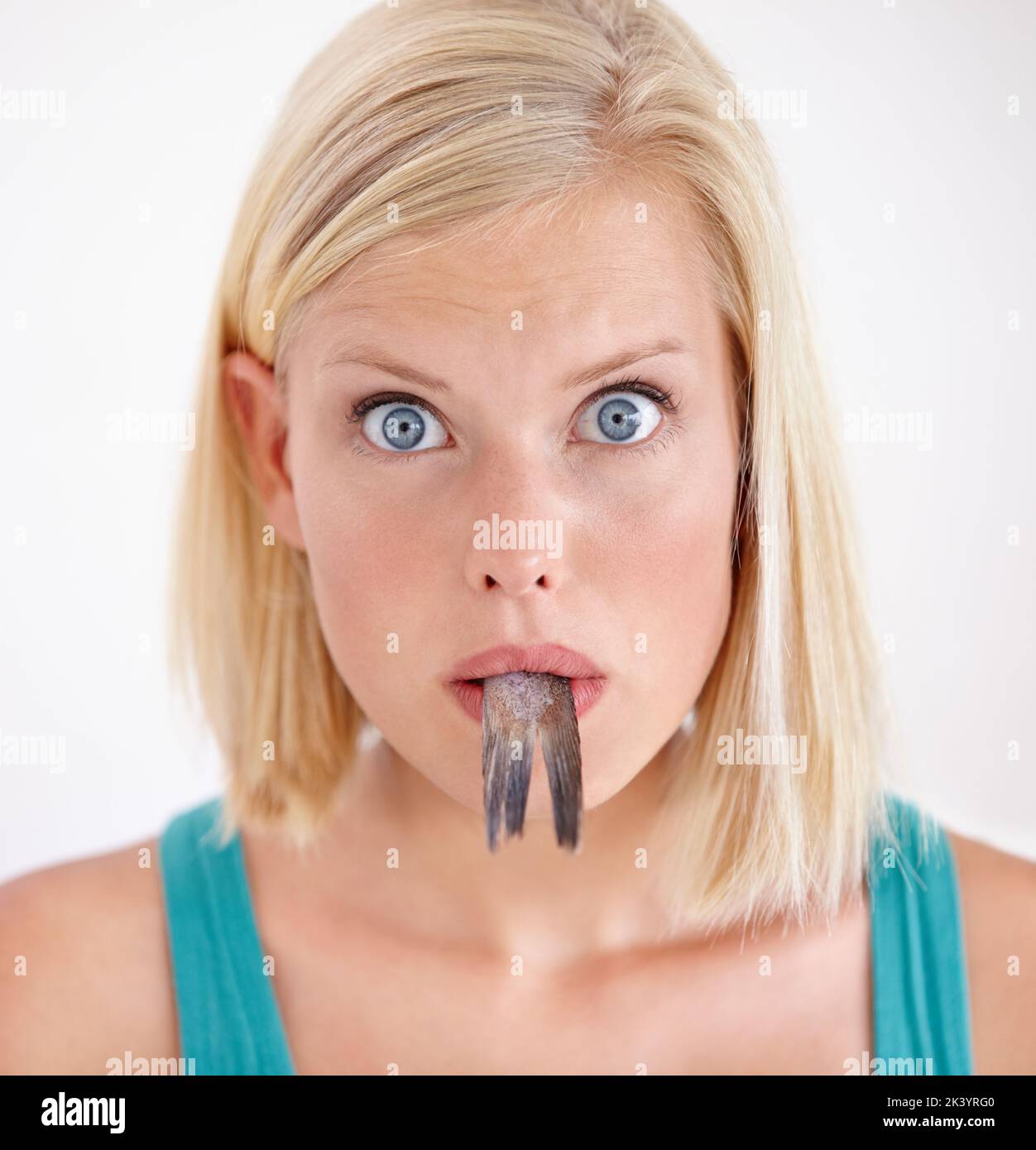 Eating a tasteless fish. Portrait of a young woman eating a whole fish. Stock Photo