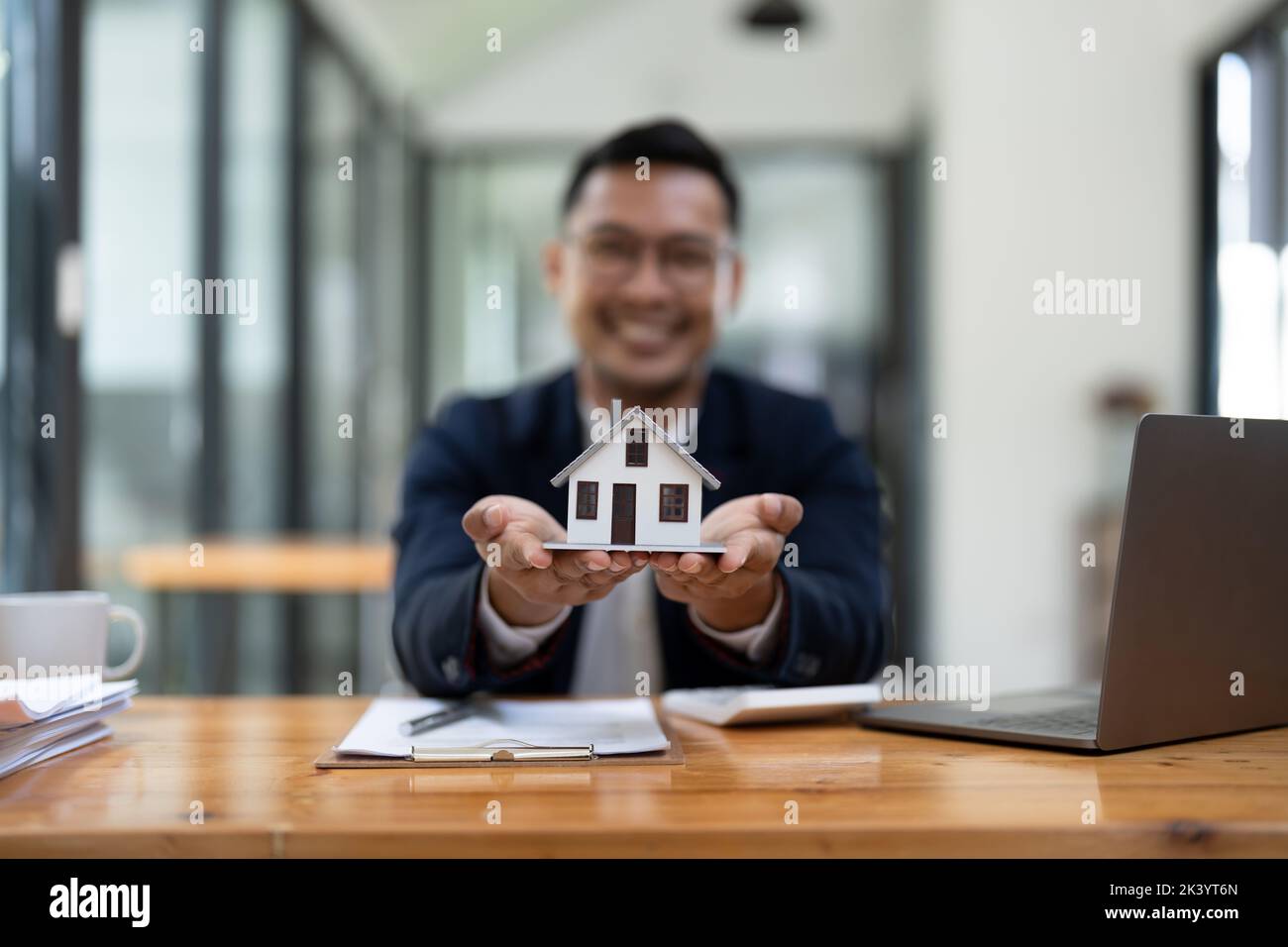 Close up view of young man holding house model. Property insurance and real estate concept. Stock Photo