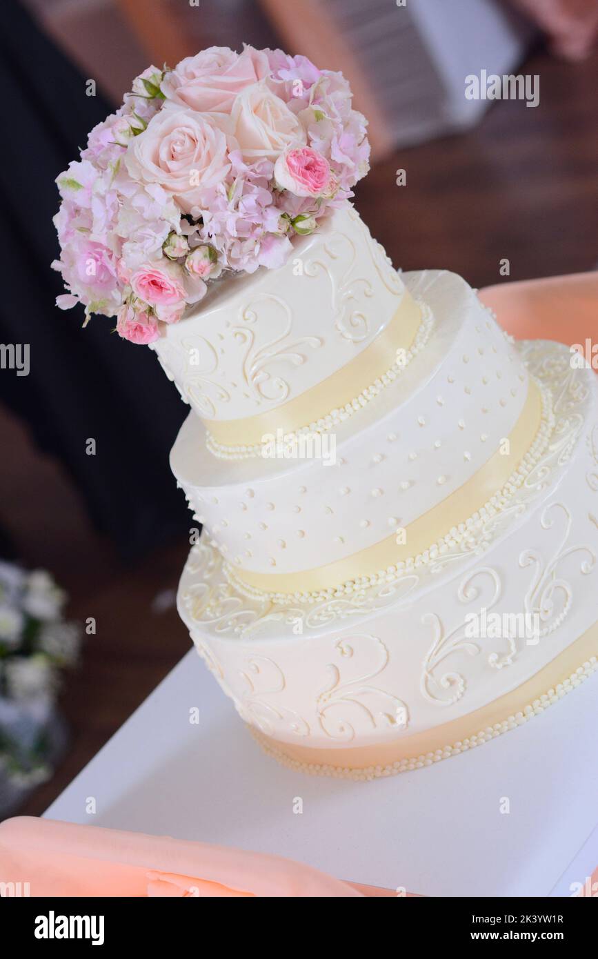 Ivory-colored wedding cake with a flower bouquet on top Stock Photo