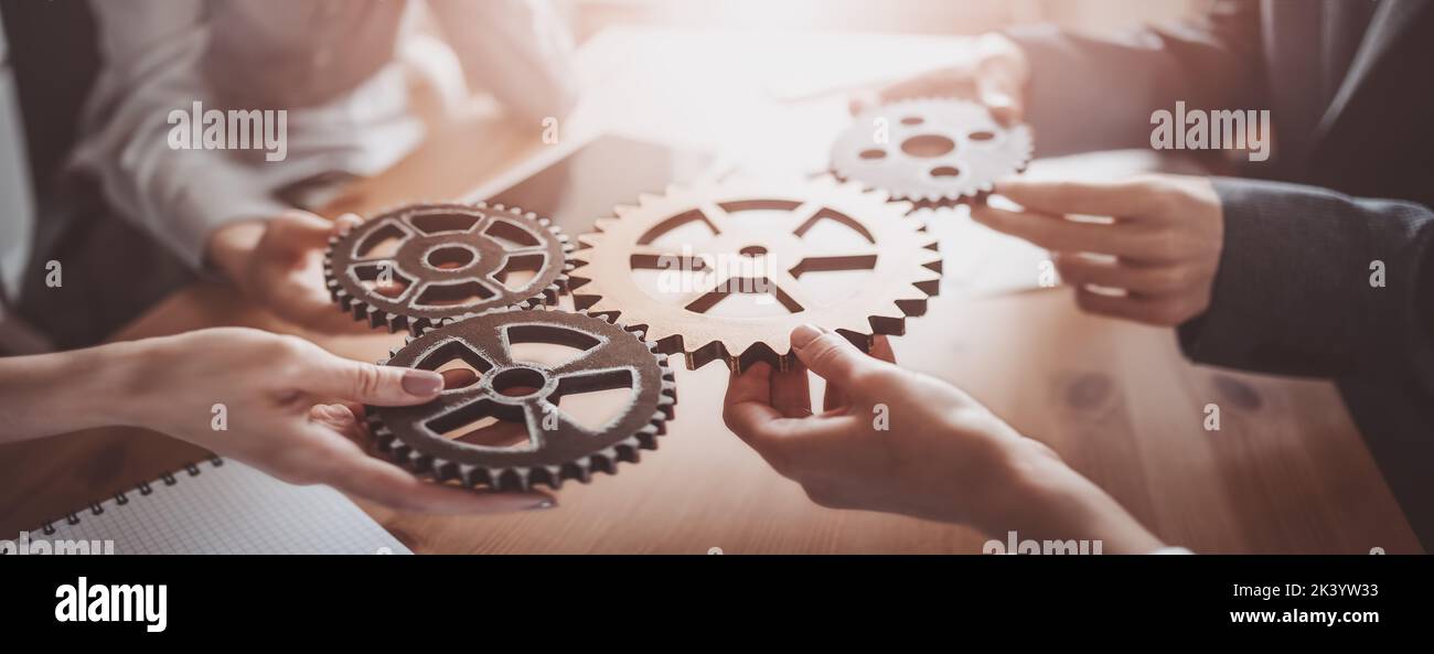 Group of people working in the office while putting together cogwheels. Stock Photo