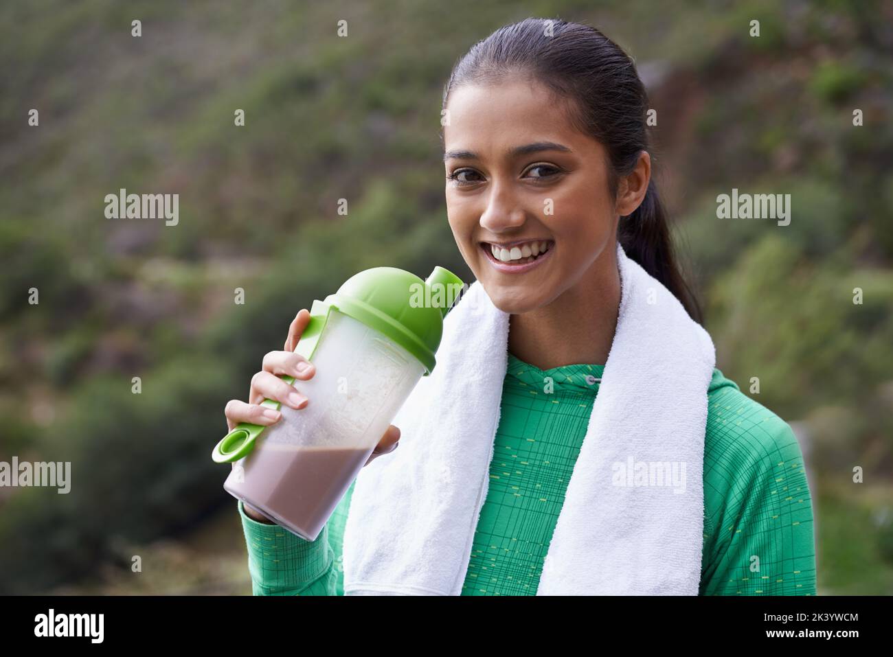 Staying healthy. A young ethnic woman drinking a sports drink outdoors