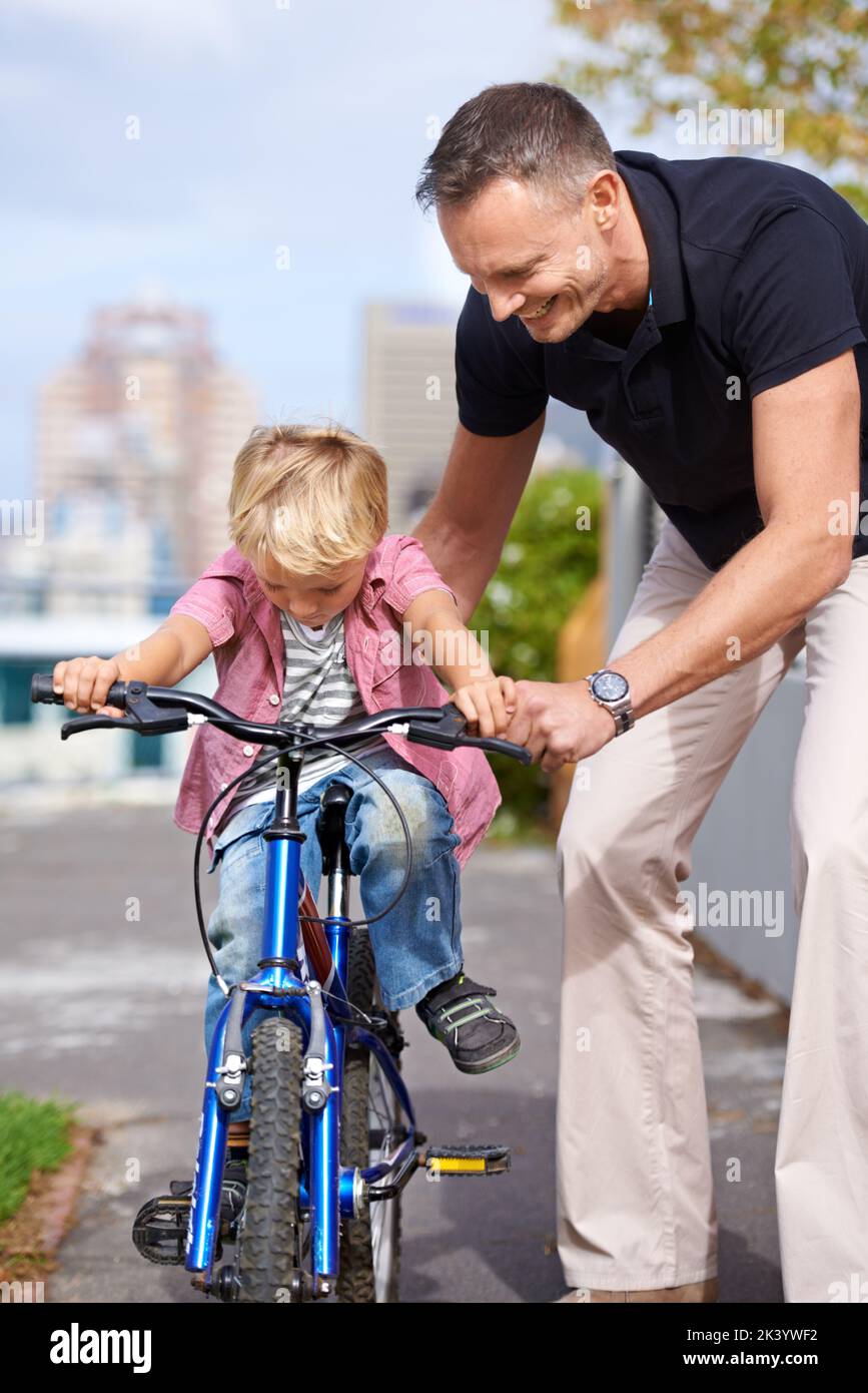 His first bike ride. A father teaching his young son to ride a bike. Stock Photo