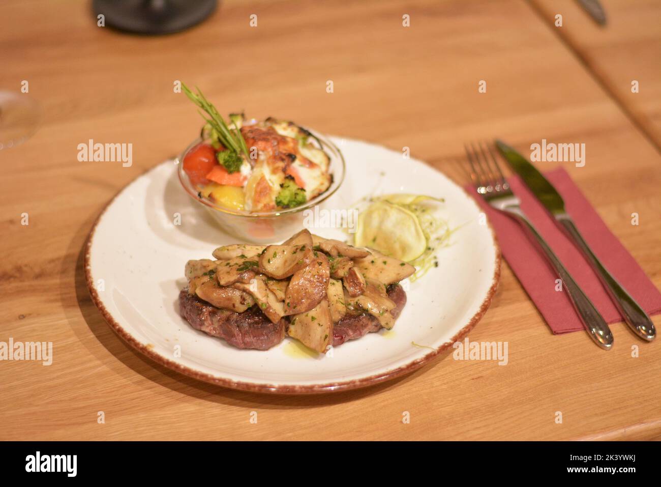 Pork neck covered with sauteed mushrooms, wedges potato with rosemary and wheat germ as decoration. Stock Photo