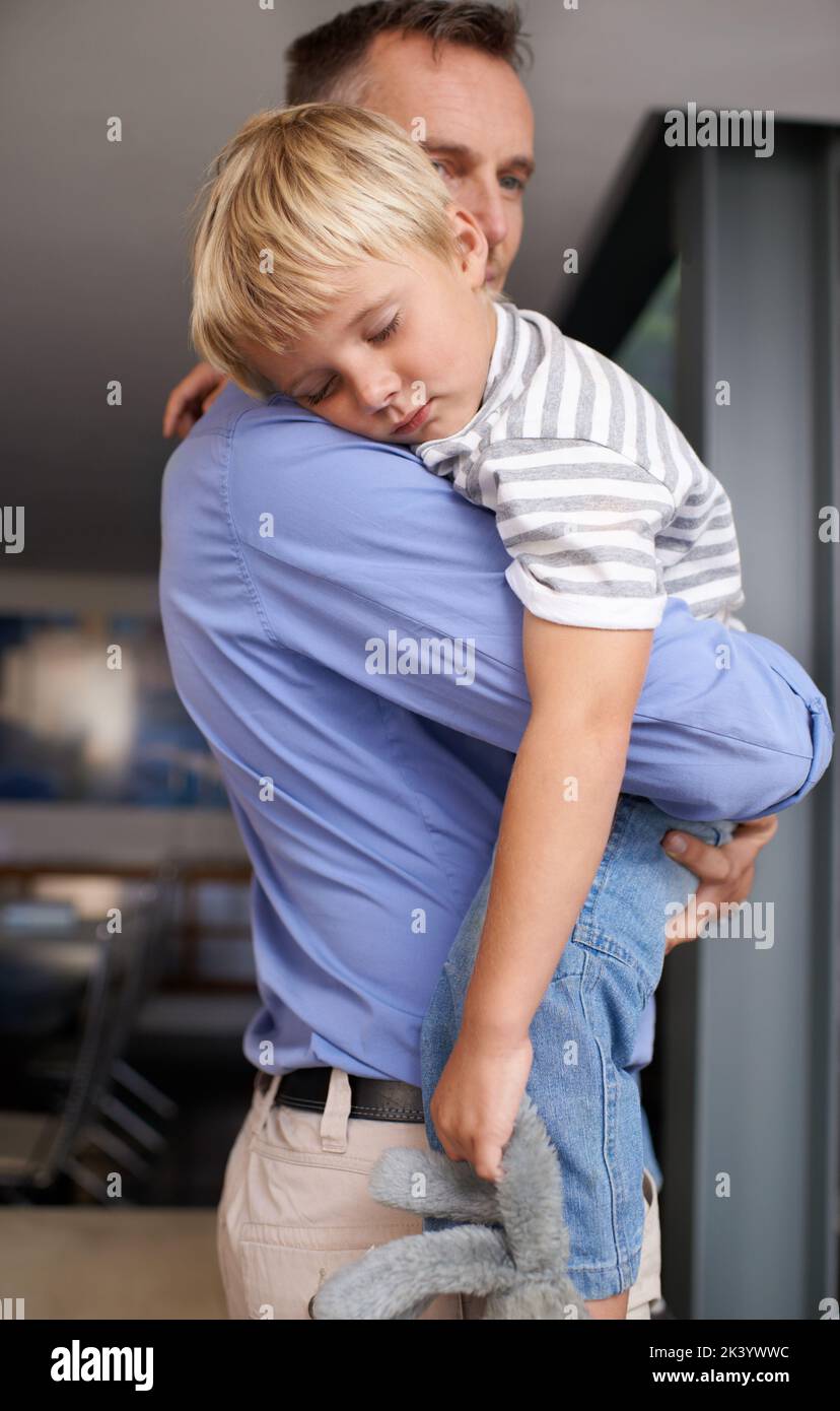 Daddys shoulder makes the best pillow. A mature father coming home from work and hugging his exhausted little boy. Stock Photo