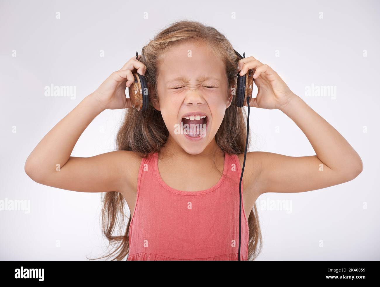 Ouch. A young girl screaming while wearing a pair of headphones. Stock Photo