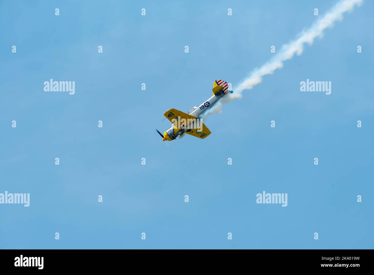 Lowangle view of a propeller plane leaving contrail behind Stock Photo