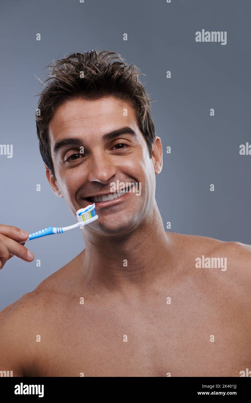 Hes committed to dental hygiene. Studio portrait of a bare-chested young man about to brush his teeth. Stock Photo