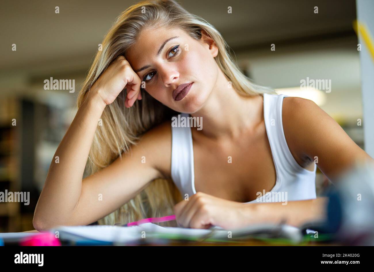 Exhausted young female studying and preparing for exam in college library. Education people concept Stock Photo