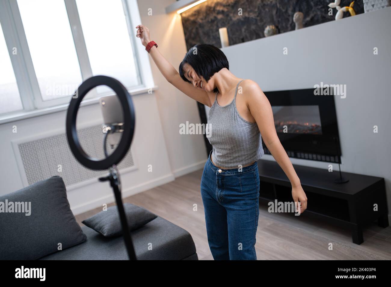 Joyful young vlogger live-streaming her dance class to online followers Stock Photo