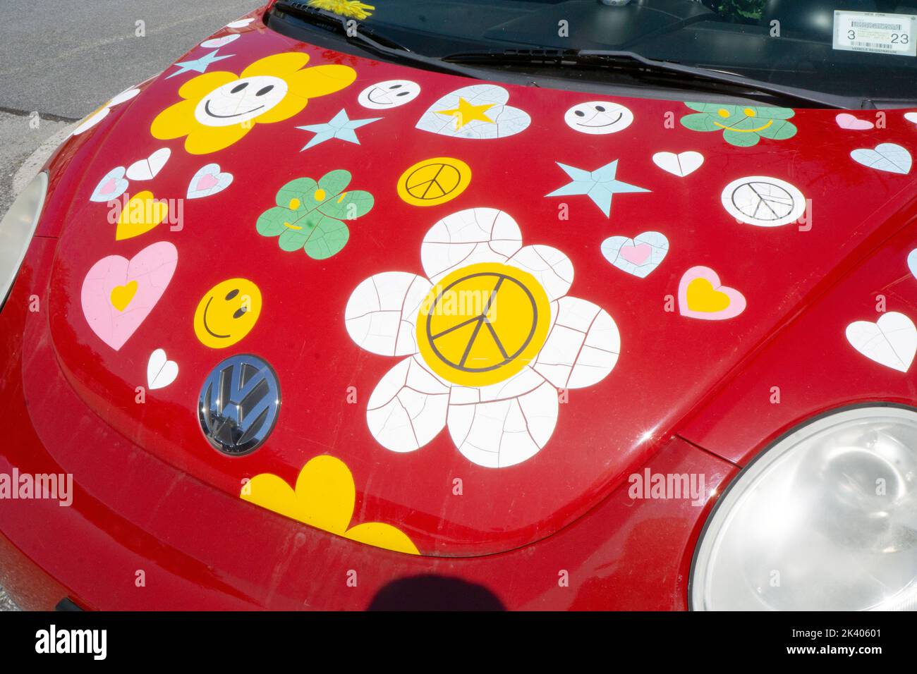 A red 2010 Volkswagen bug covered with stickers reminiscent of the 1960s. In a parking lot in Chappaqua, New York. Stock Photo
