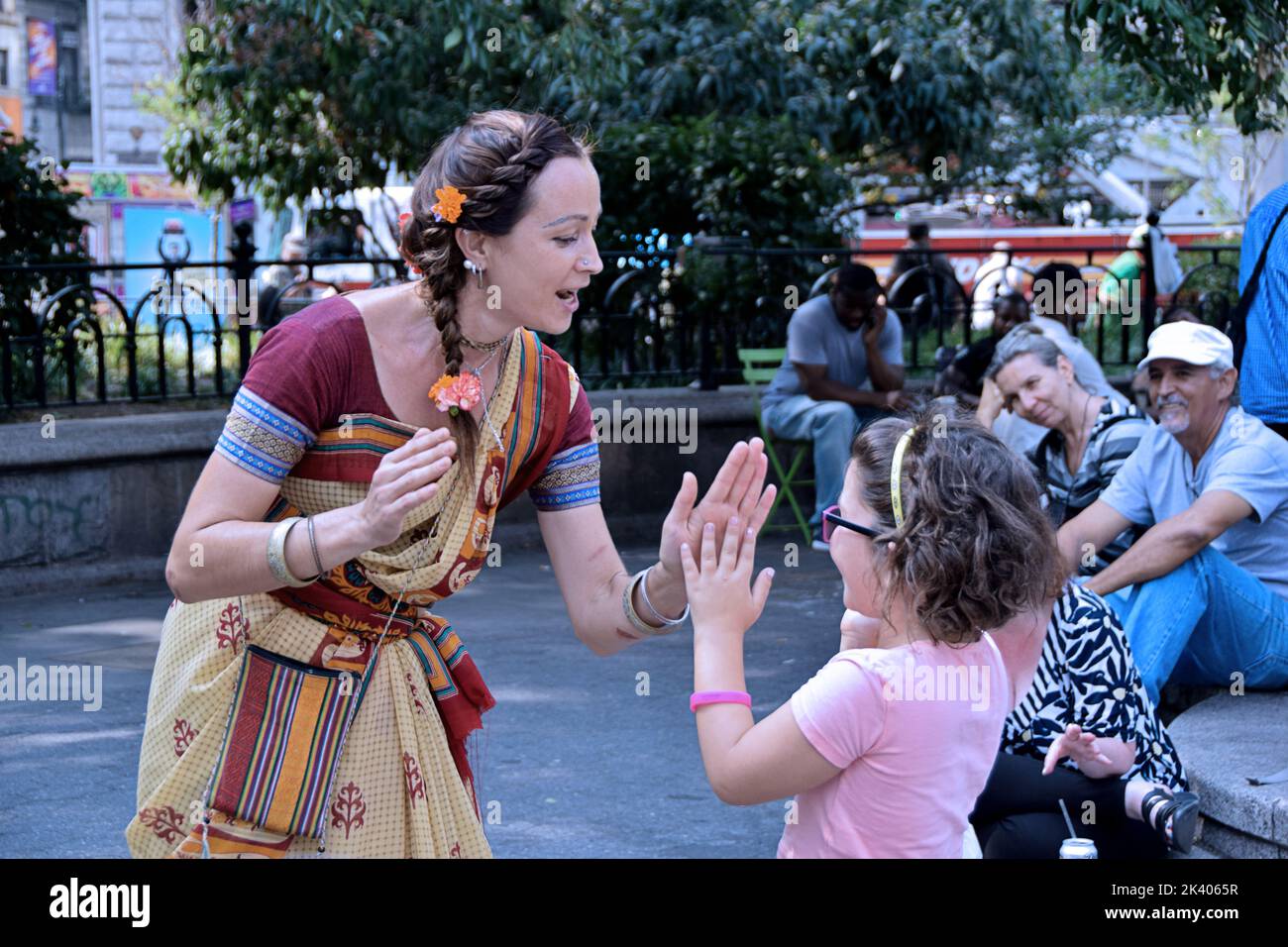 A Latvian Hare Krishna devotee plays patty cake with the daughter of a passer bye in Union Square Park, New York City Stock Photo