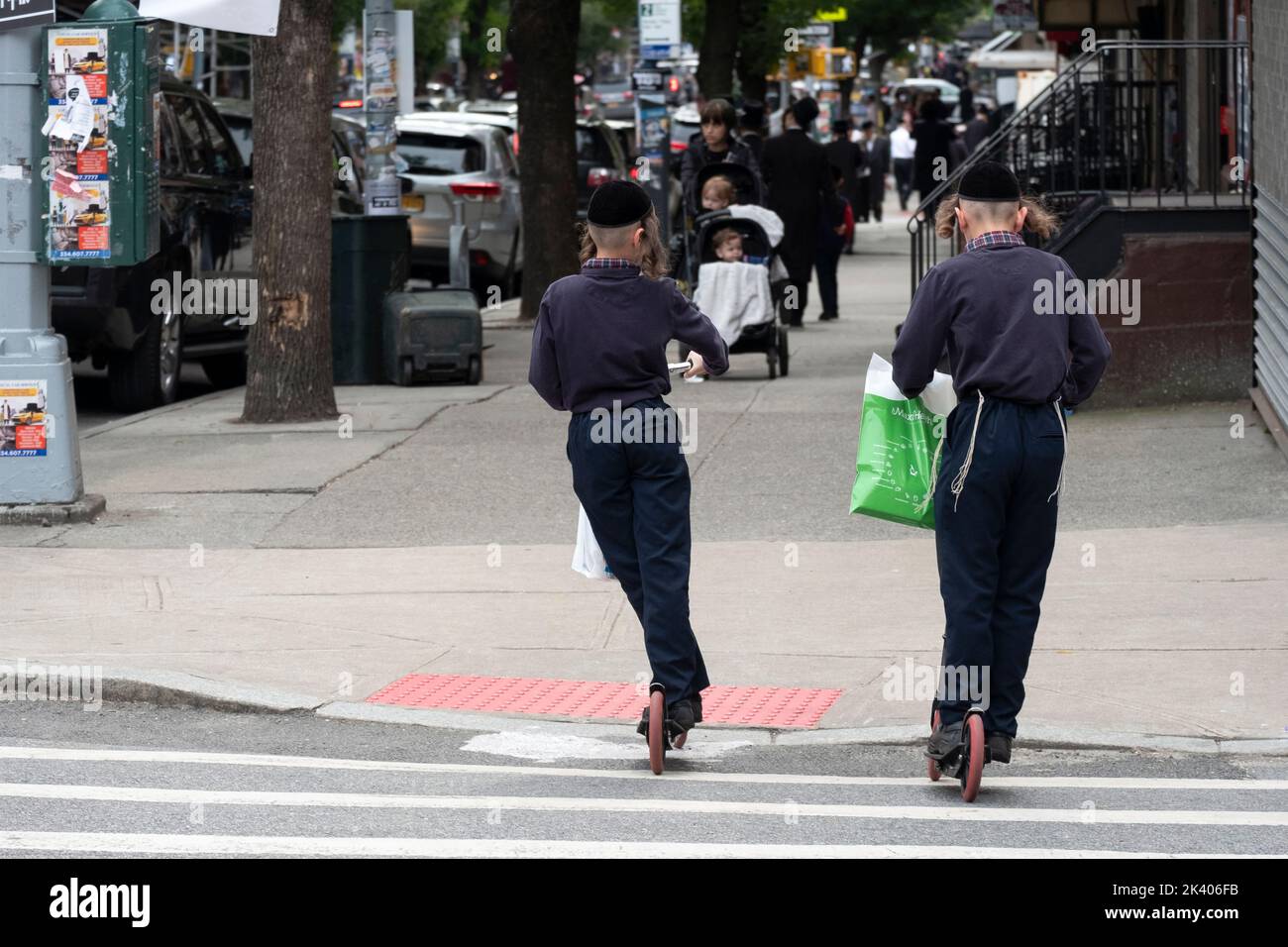 Hasidic brothers ride their scooters on Lee avenue on the day before Jewish New Year. In Williamsburg, Brooklyn, New York City. Stock Photo