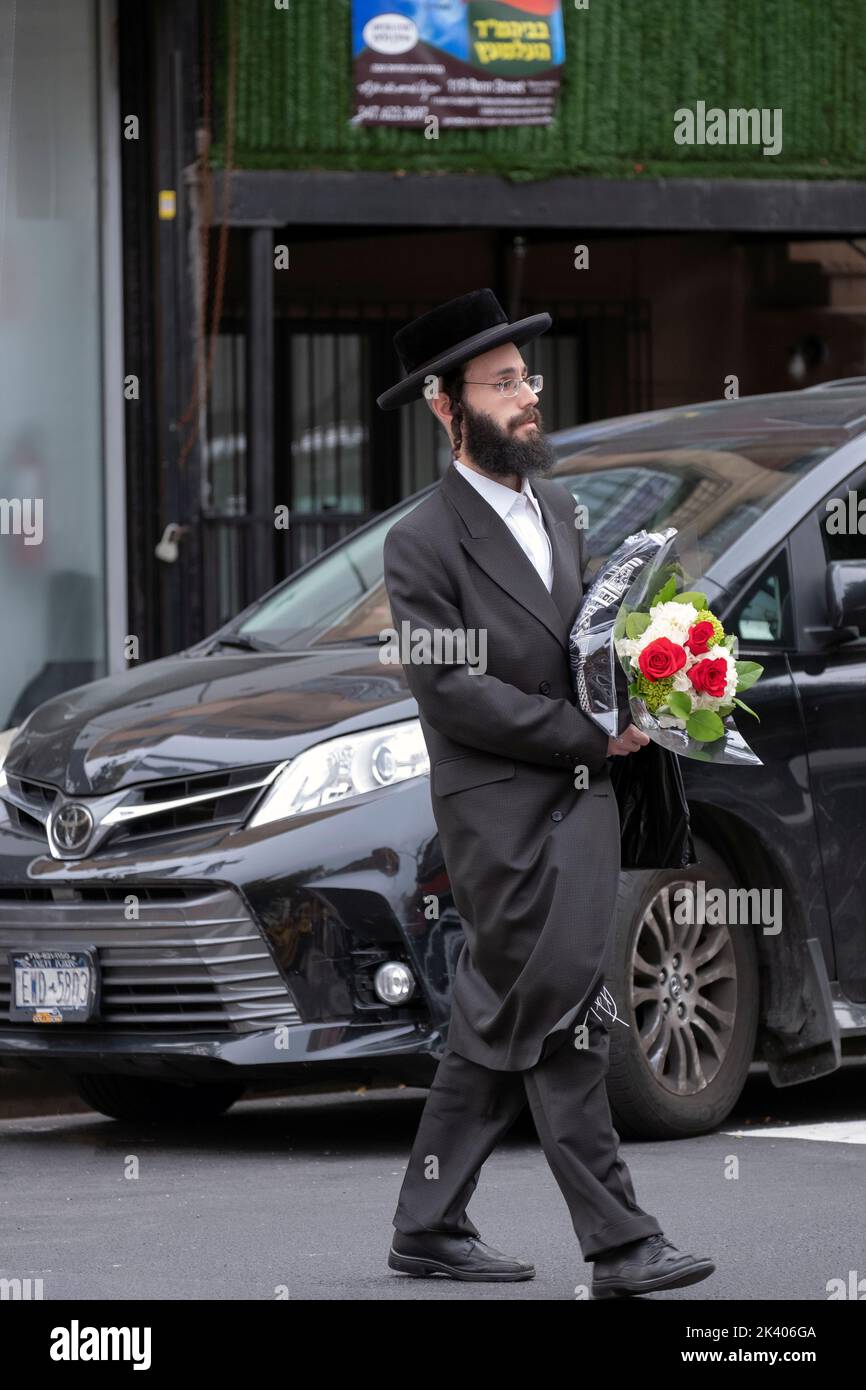 On the day before Rosh Hashana, the Jewish New Year, an orthodox man heads home with flowers. In Williamsburg, Brooklyn, New York. Stock Photo