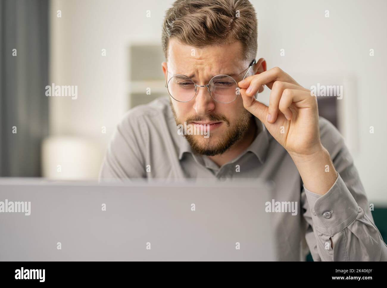 Young bearded man look closely at laptop, focused man use computer, coder working at home Stock Photo