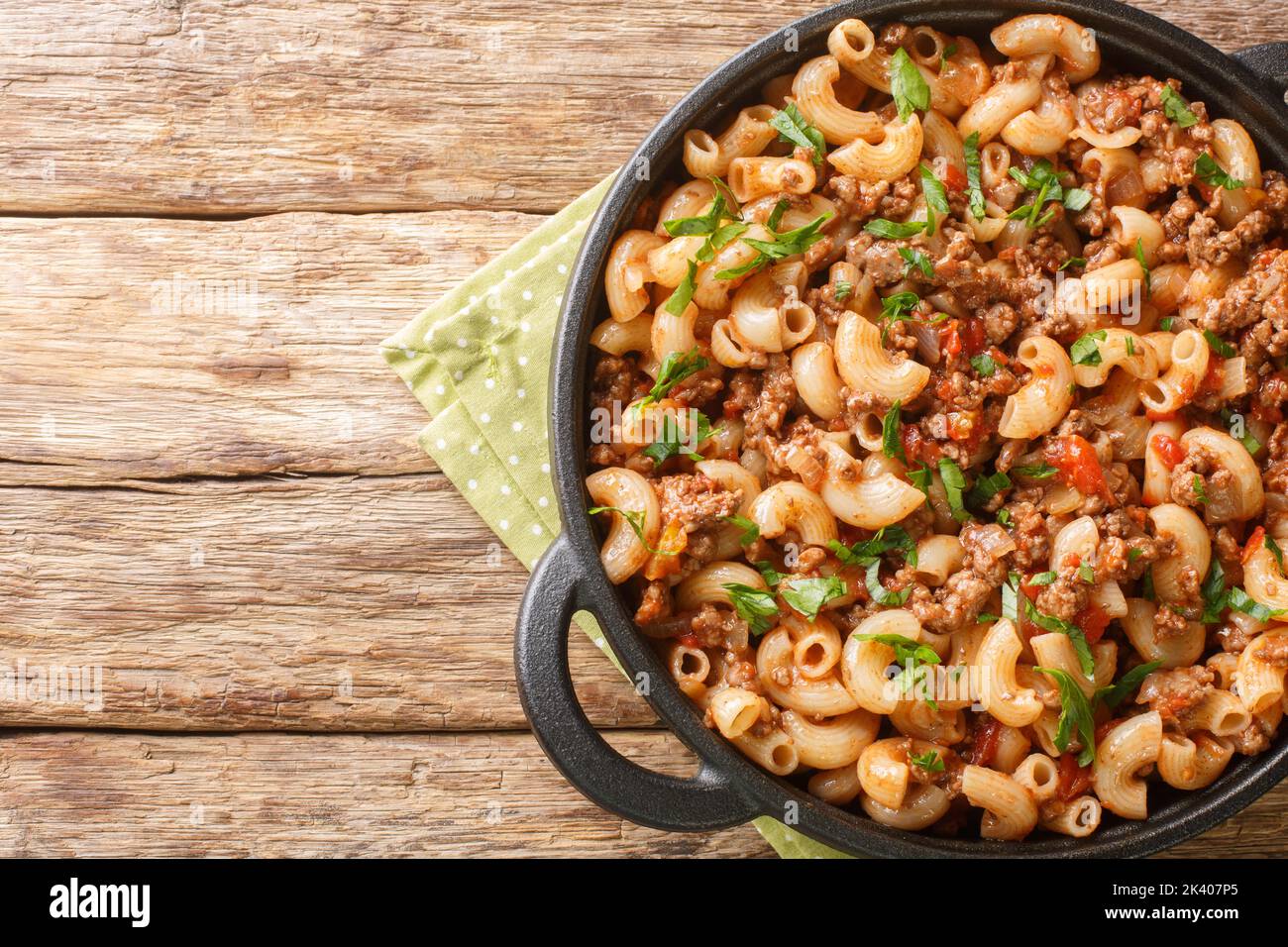 Hamburger Macaroni with with vegetables and cheese closeup in the pan on the wooden table. Horizontal top view from above Stock Photo