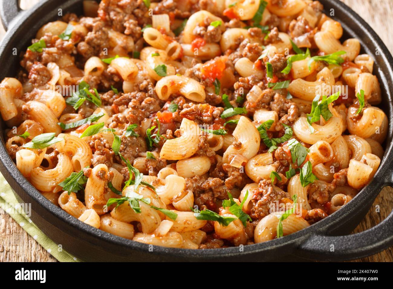 Hamburger Macaroni with with vegetables and cheese closeup in the pan on the wooden table. Horizontal Stock Photo