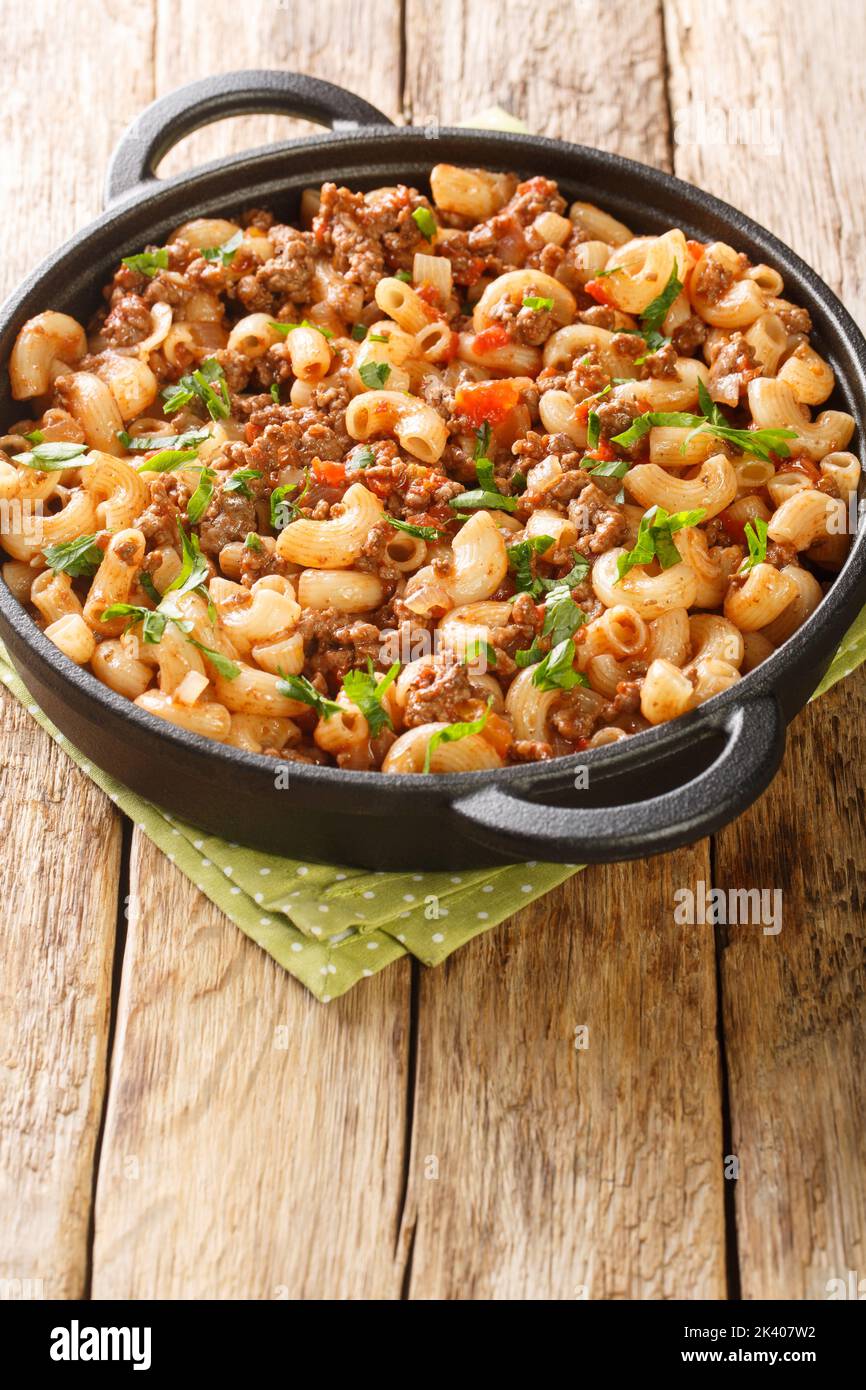 Hamburger and Macaroni closeup in the pan on the wooden table. Vertical Stock Photo