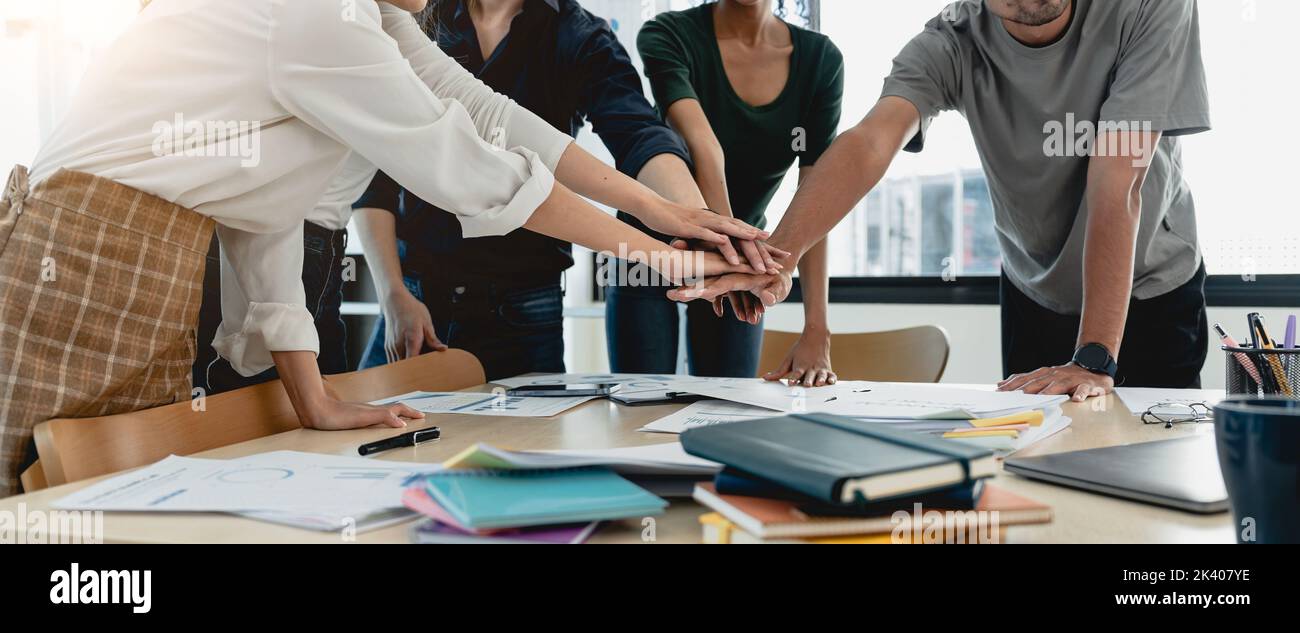 Teamwork business concept. Close up view of group of three coworkers join hand together during their meeting. Stock Photo