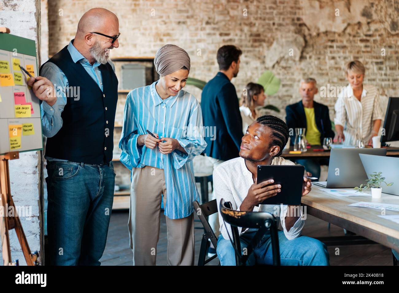 Multi-Ethnic office workspace room - Businesspeople meeting gather around the business model canvas - Diverse team of creative professionals talk, bra Stock Photo