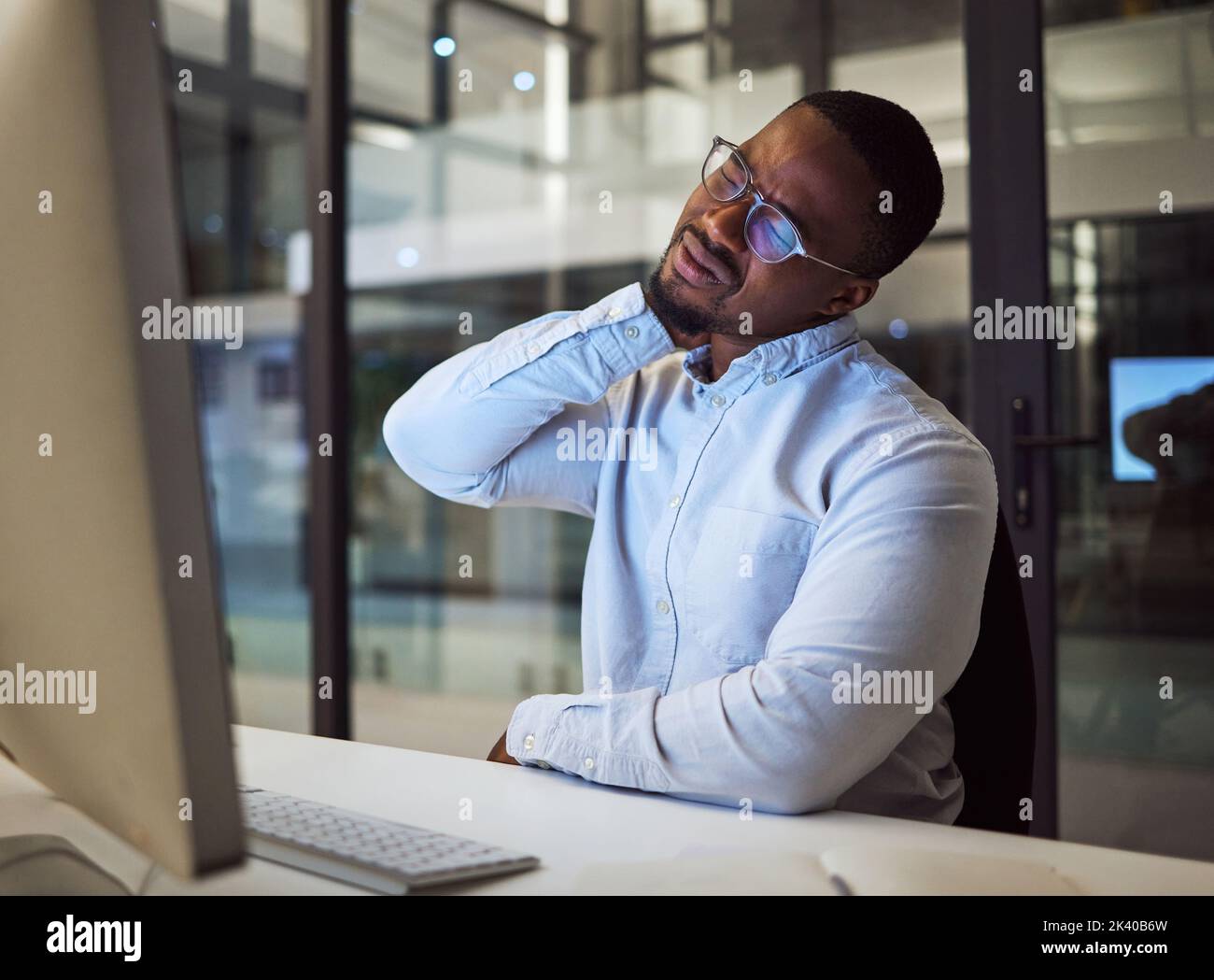 Burnout, stress and neck pain by businessman working on a computer late in office, injury and discomfort. Corporate employee suffering from hurt and Stock Photo