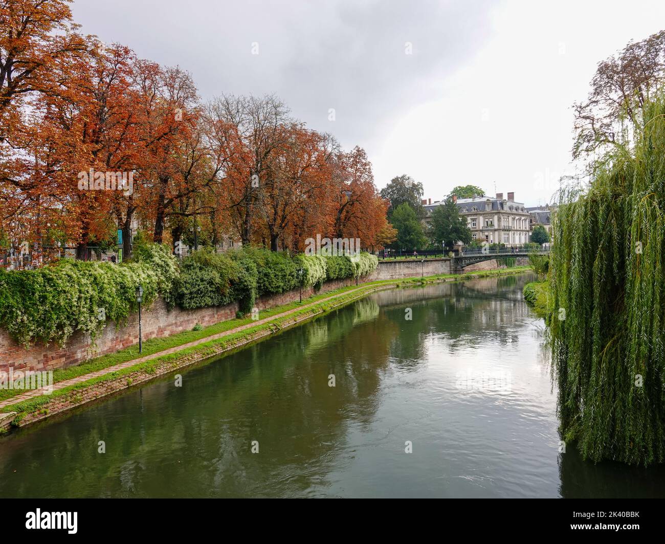 Autumn colors and lush green plants, looking up the Canal du Faux-Rempart towards the Passerelle des Juifs, Strasbourg, France. Stock Photo