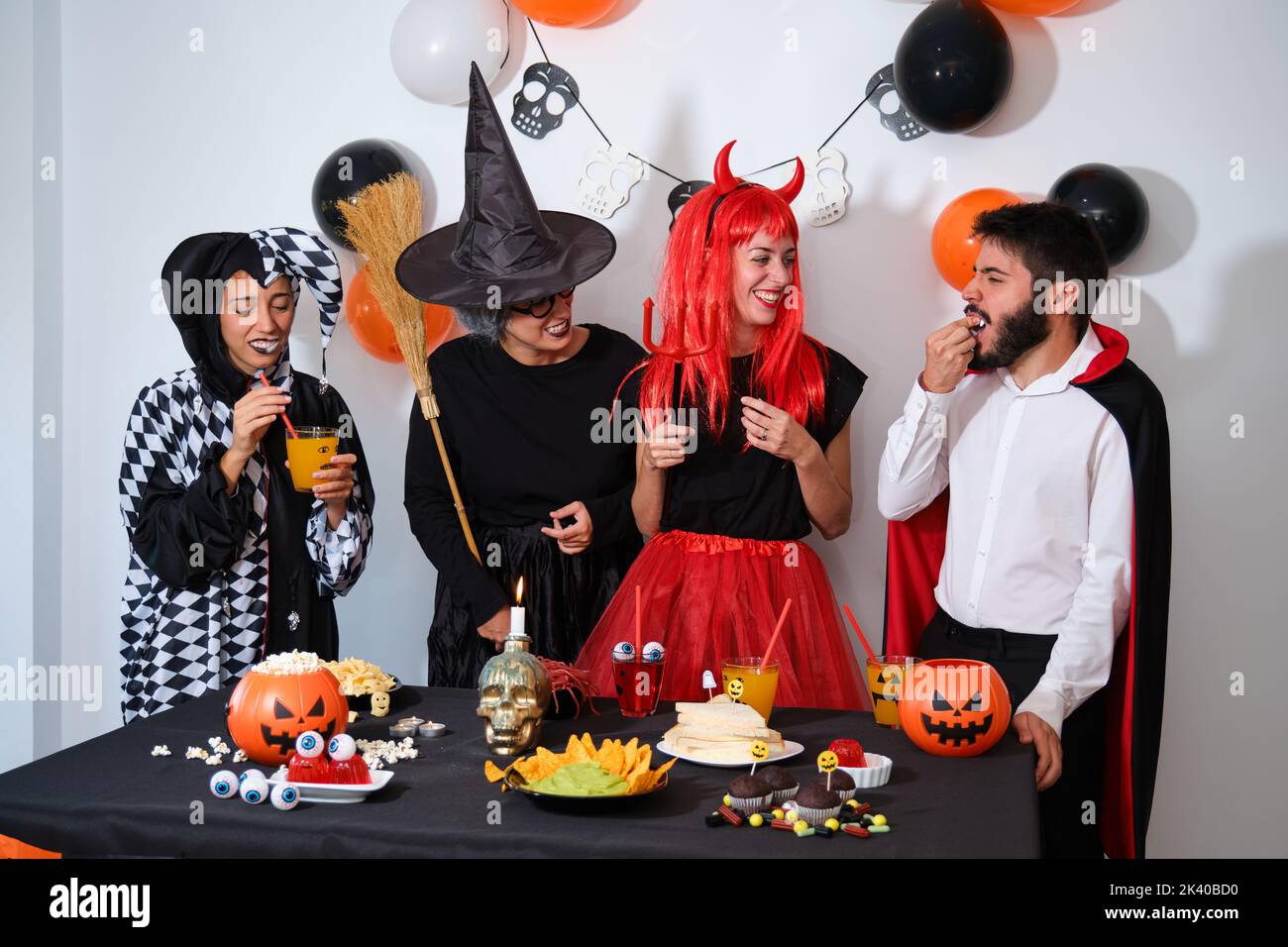 Four people talking and laughing at a costume Halloween party. Stock Photo
