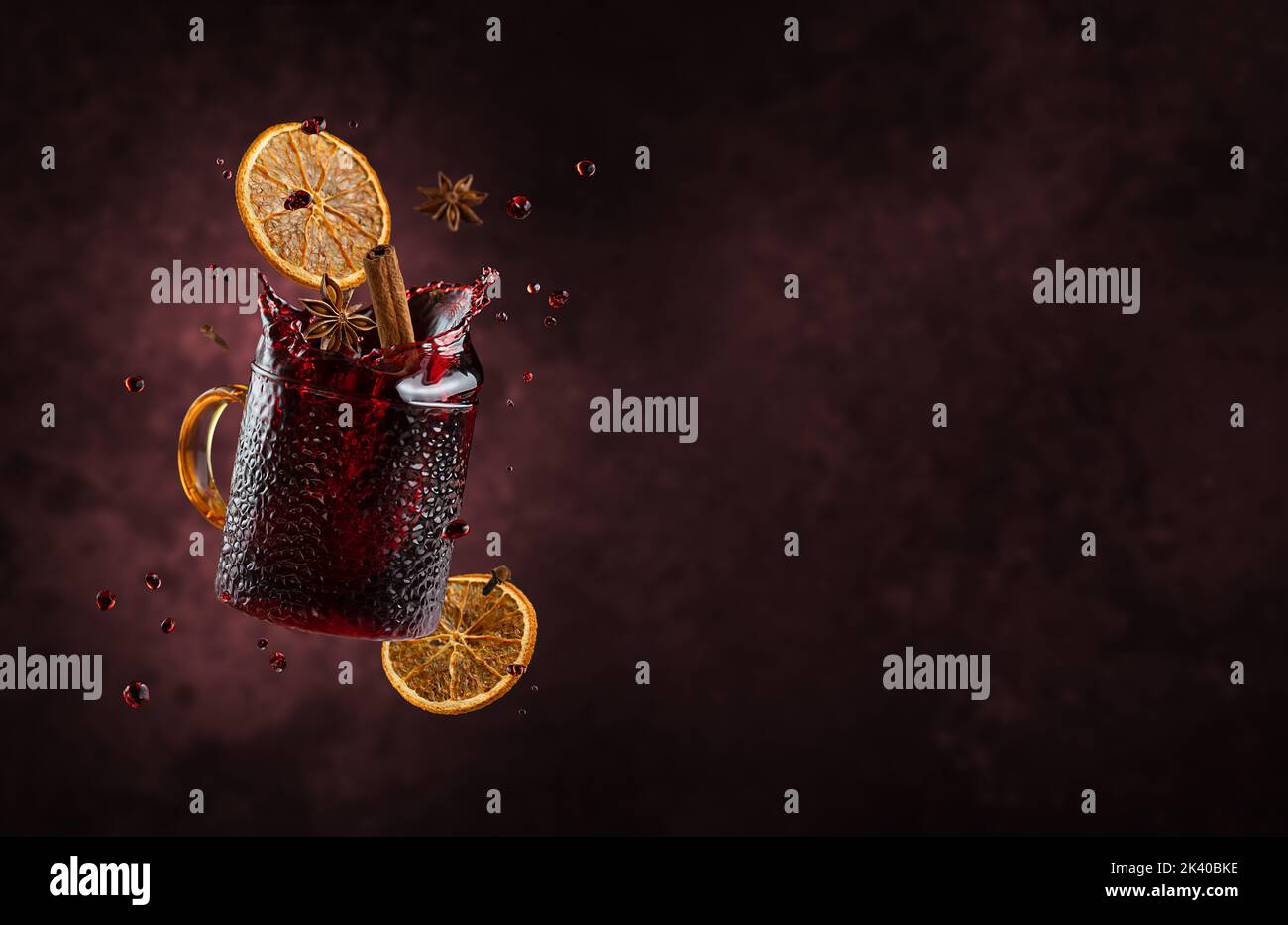 Mulled wine with splashes and flying ingredients on dark background. Copy space Stock Photo