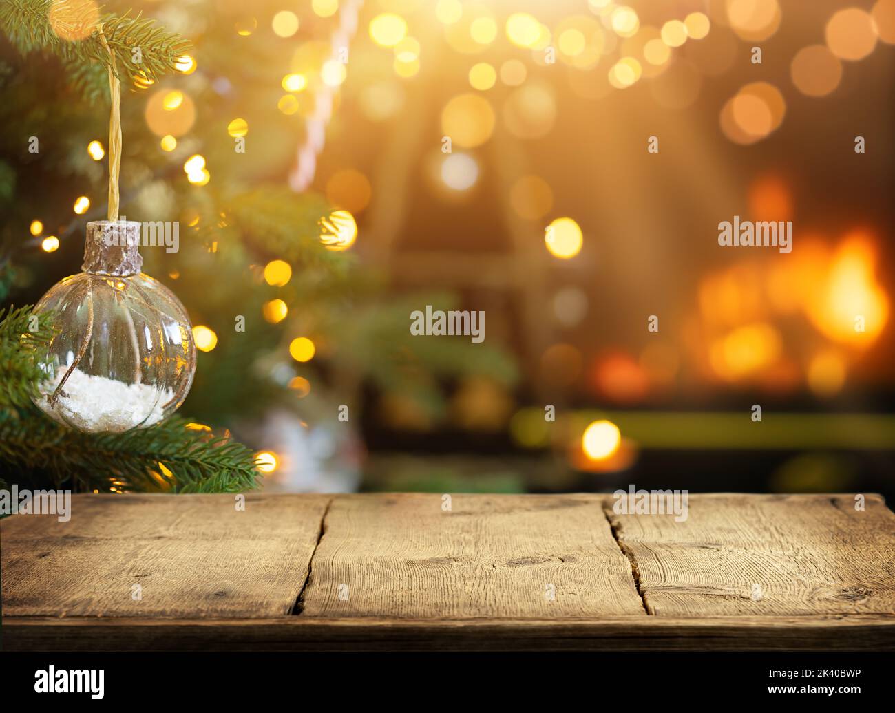 Empty wooden table on Christmas ornaments background with fireplace. Copy space. Stock Photo