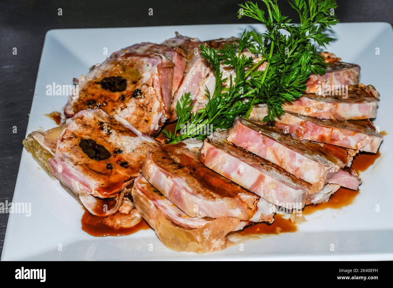 Rolled meatloaf with sauce, presented in slices on a white plate. Stock Photo