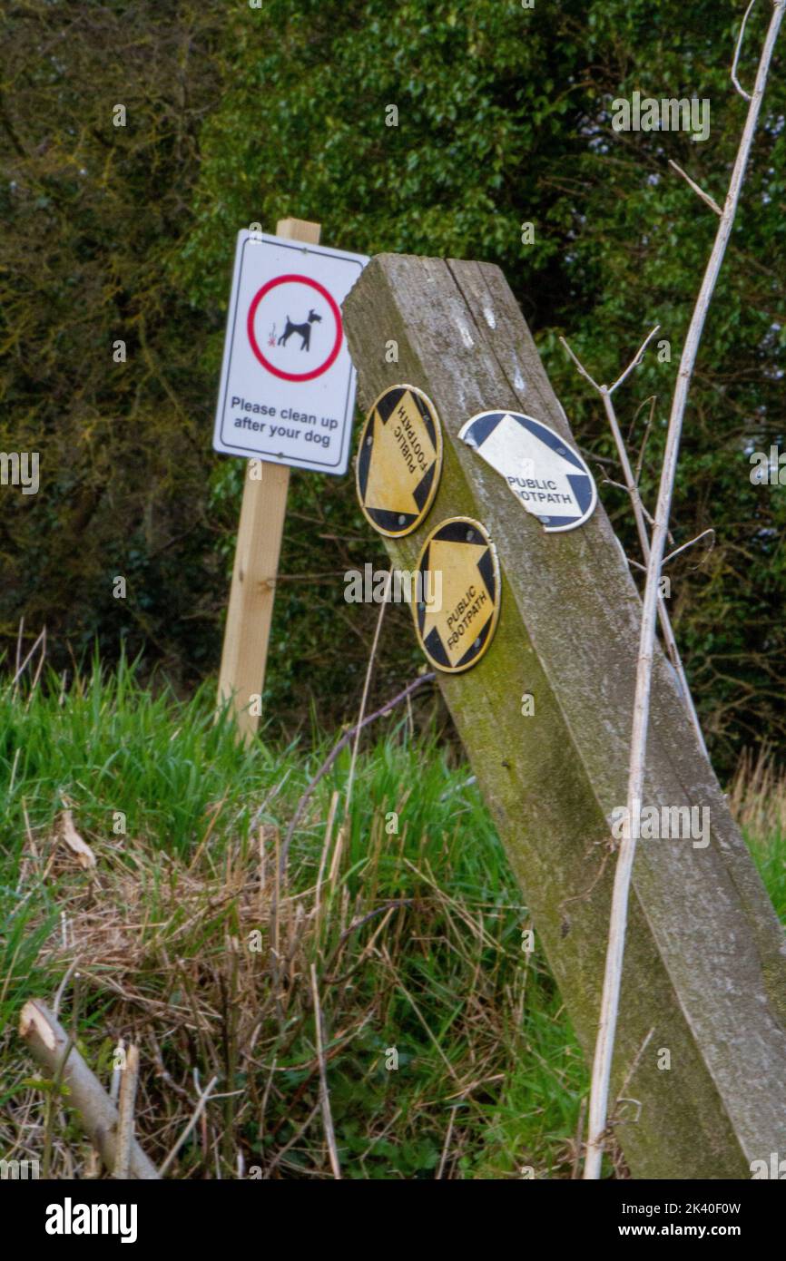 Two signs including a collapsing post with public footpath direction arrows Stock Photo
