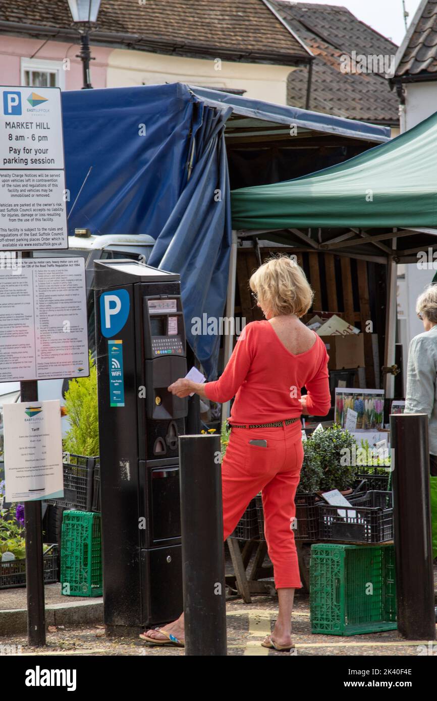 Woman dressed all in red paying to park in Framlingham Suffolk on a market day Stock Photo