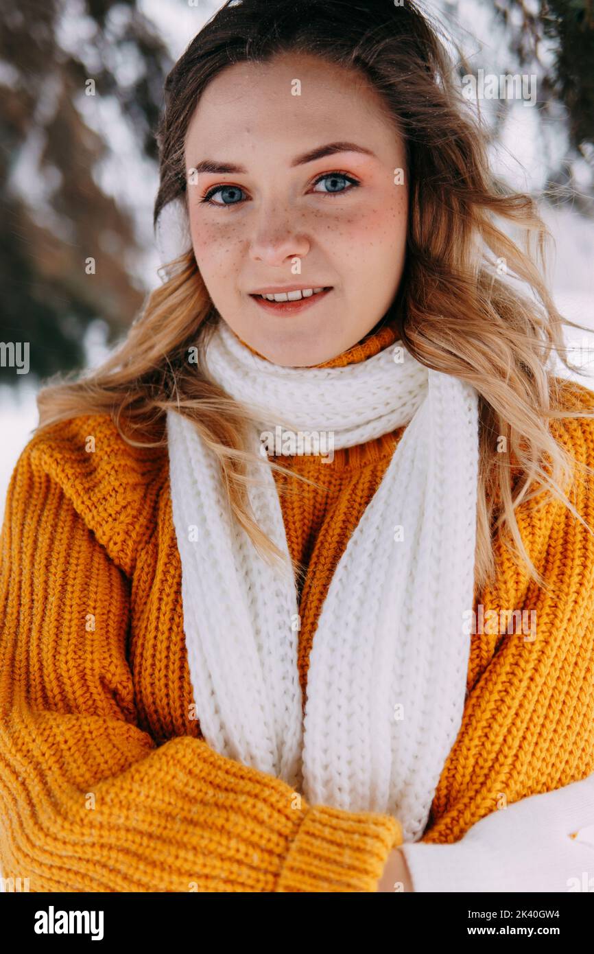 Teen blonde in a yellow sweater outside in winter. A teenage girl on a walk in winter clothes in