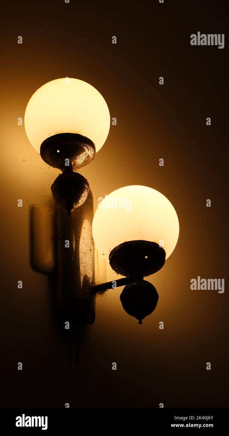lamp with two bulbs of ambient yellow lighting on the wall in the dark of the night Stock Photo
