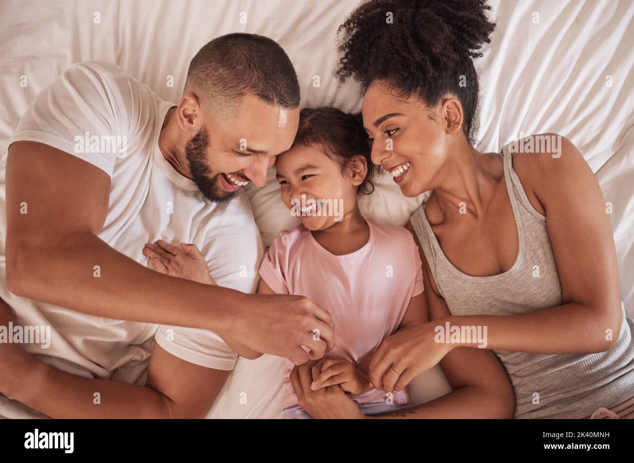 Morning, love and parents relax from above on bed with happy daughter together in Mexican house. Cheerful mother and father of young child smile in Stock Photo